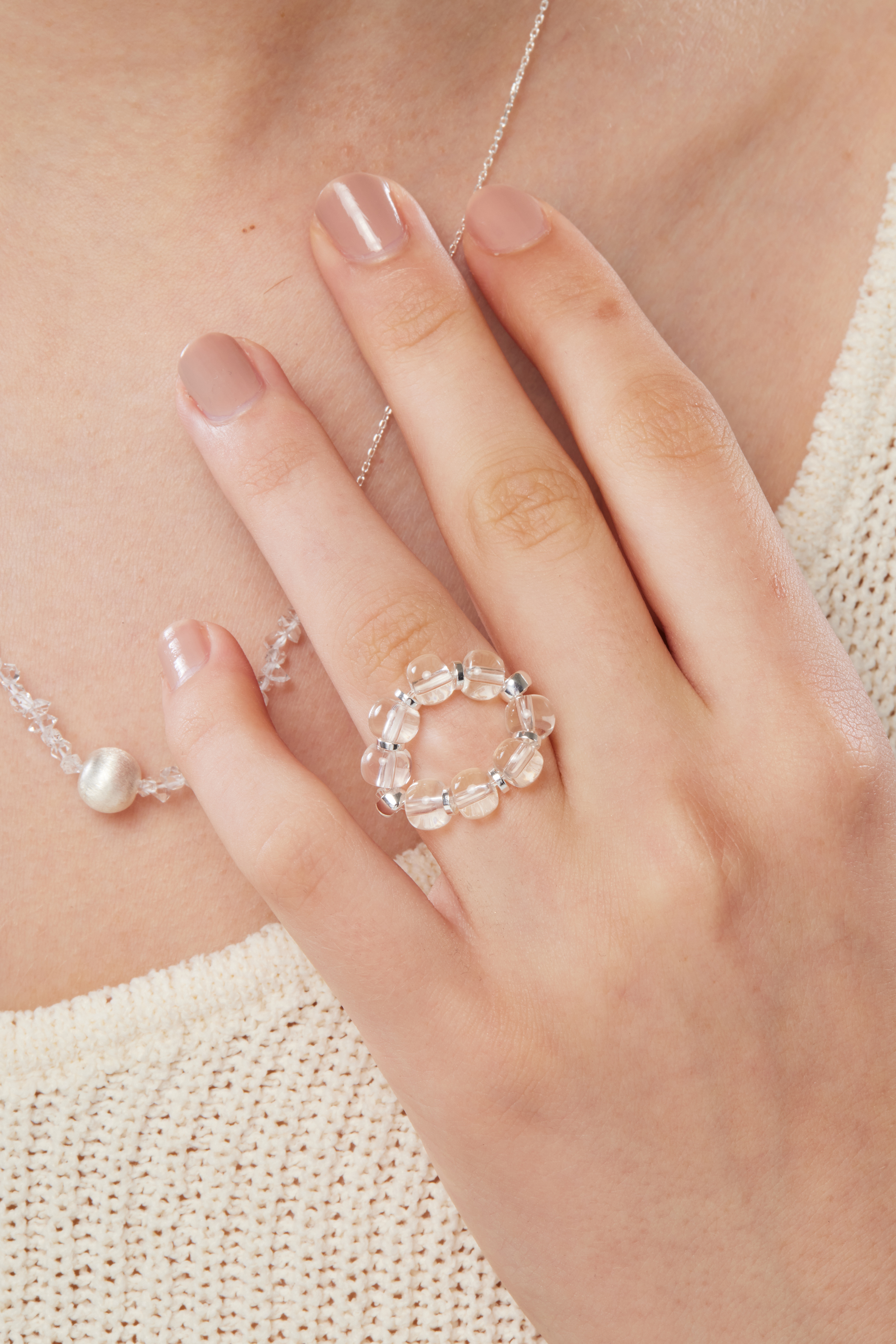 模特手部特寫，白水晶戒指佩戴於指間，晶石透亮，為手部線條增添質感焦點。