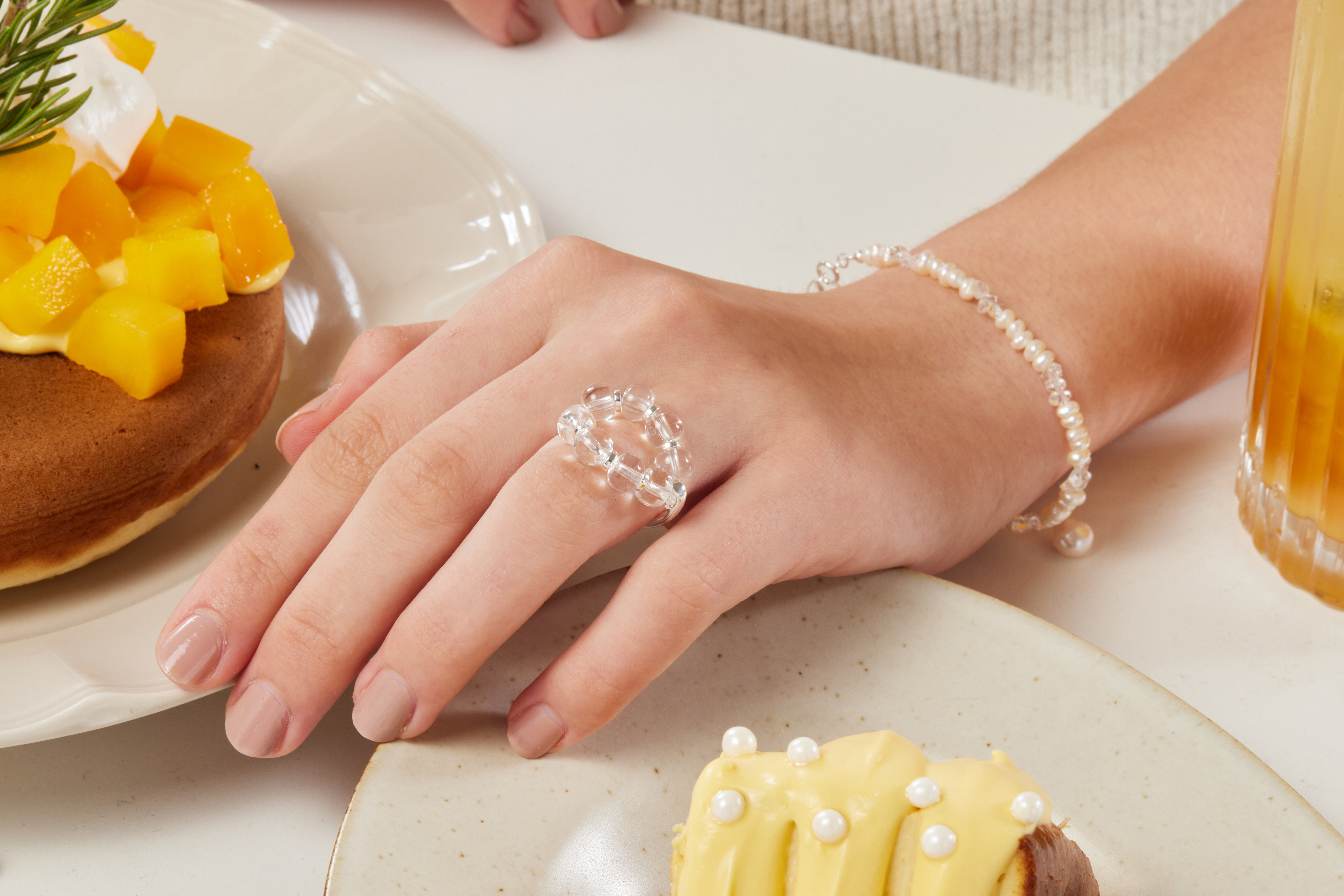 模特手部和甜點特寫，戒指在自然光下閃出細緻光芒。