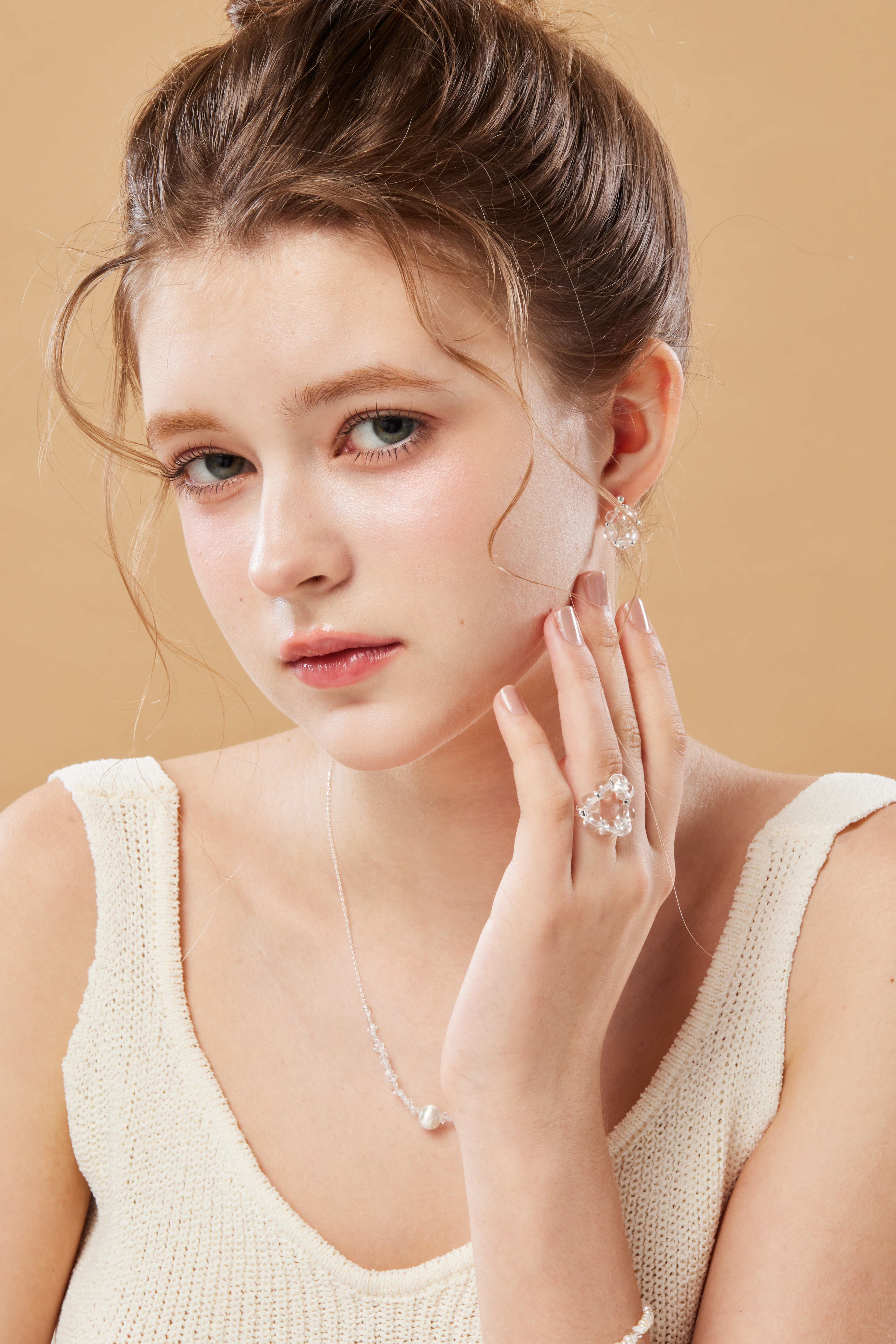 模特輕摸臉部，白水晶戒指在自然光下呈現晶瑩質感。