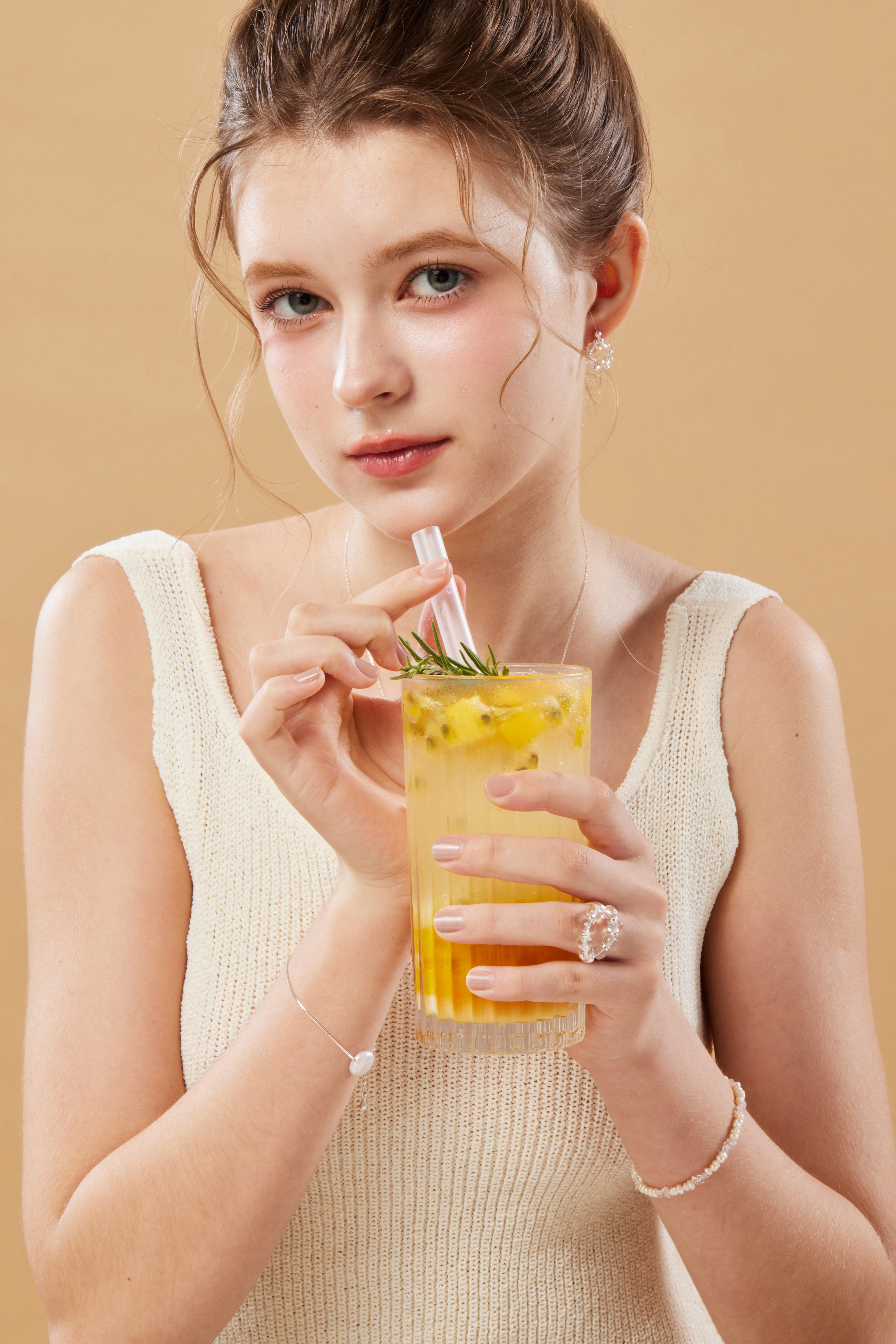 模特拿著飲品露出手部，白水晶戒指低調閃耀，為整體造型增添層次。