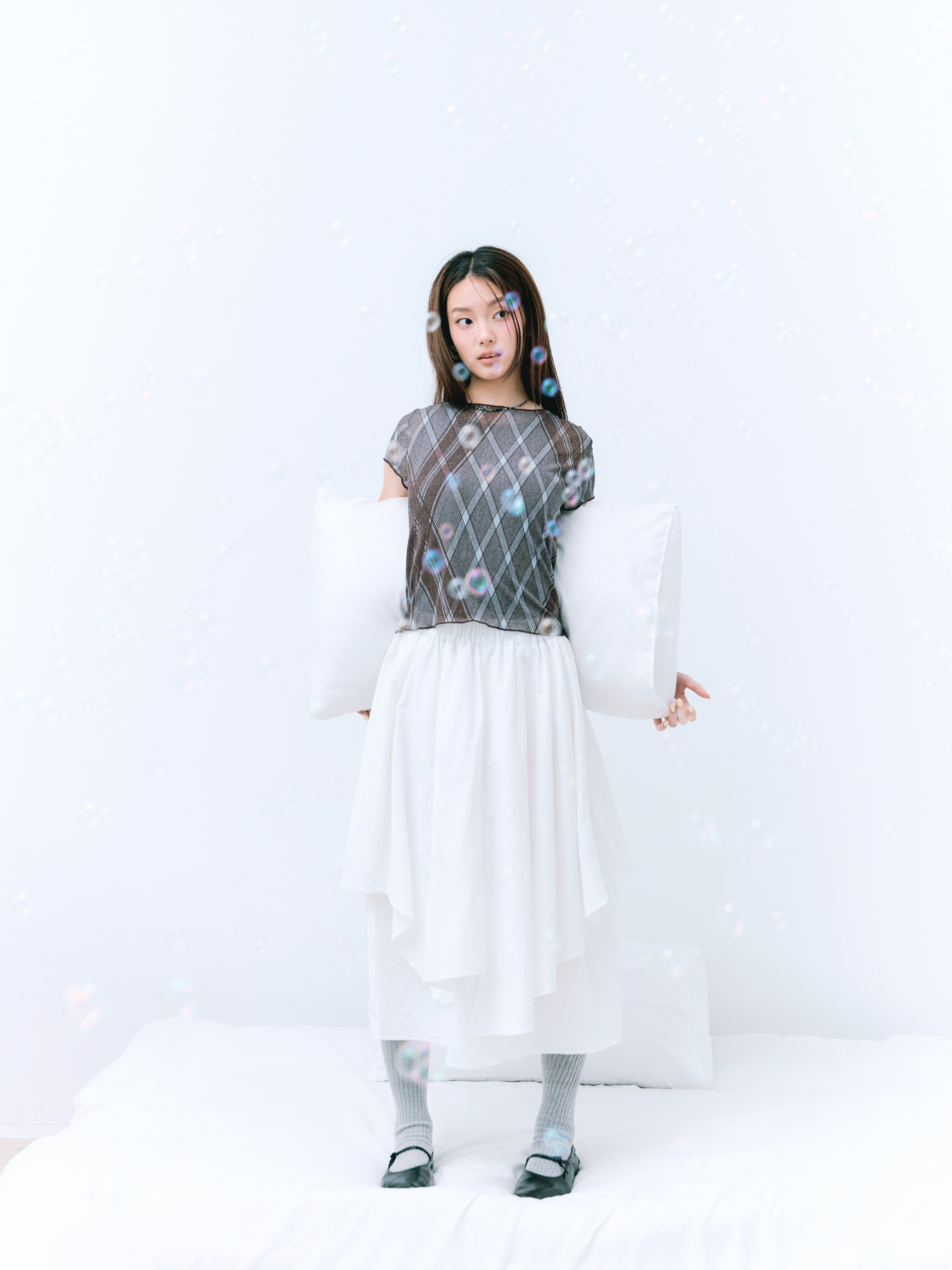 女孩身穿格紋樣式上衣，下身是不規則剪裁的白裙，空氣裡充滿泡泡，看起來很夢幻