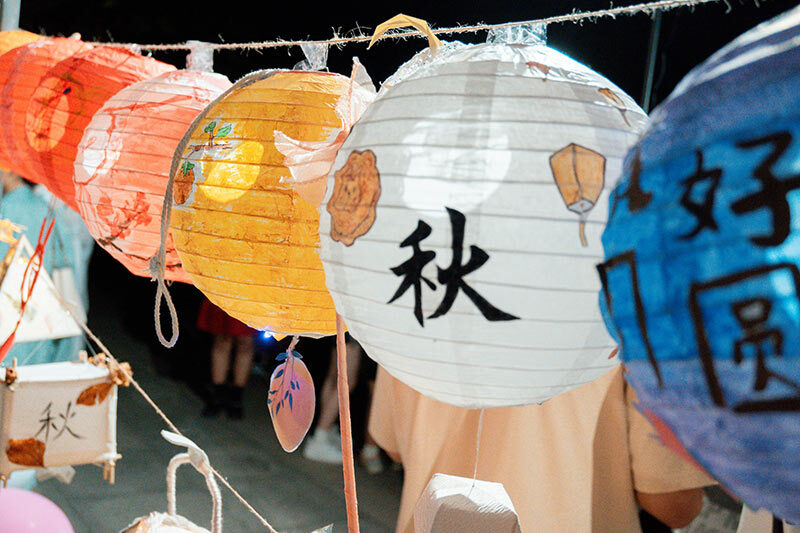 中秋節燈籠掛飾活動現場，手繪彩燈寫有‘秋’字與祝福語，營造中秋祝賀詞的節慶氛圍