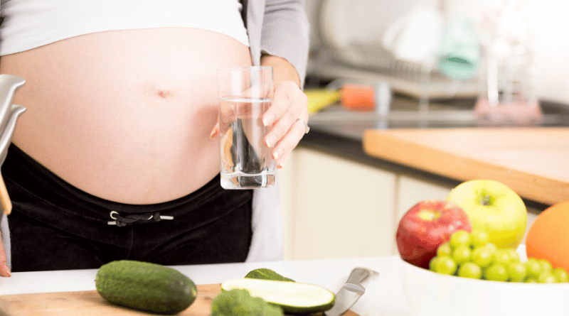 孕婦在廚房準備健康食材，強調補水與營養攝取預防妊娠紋