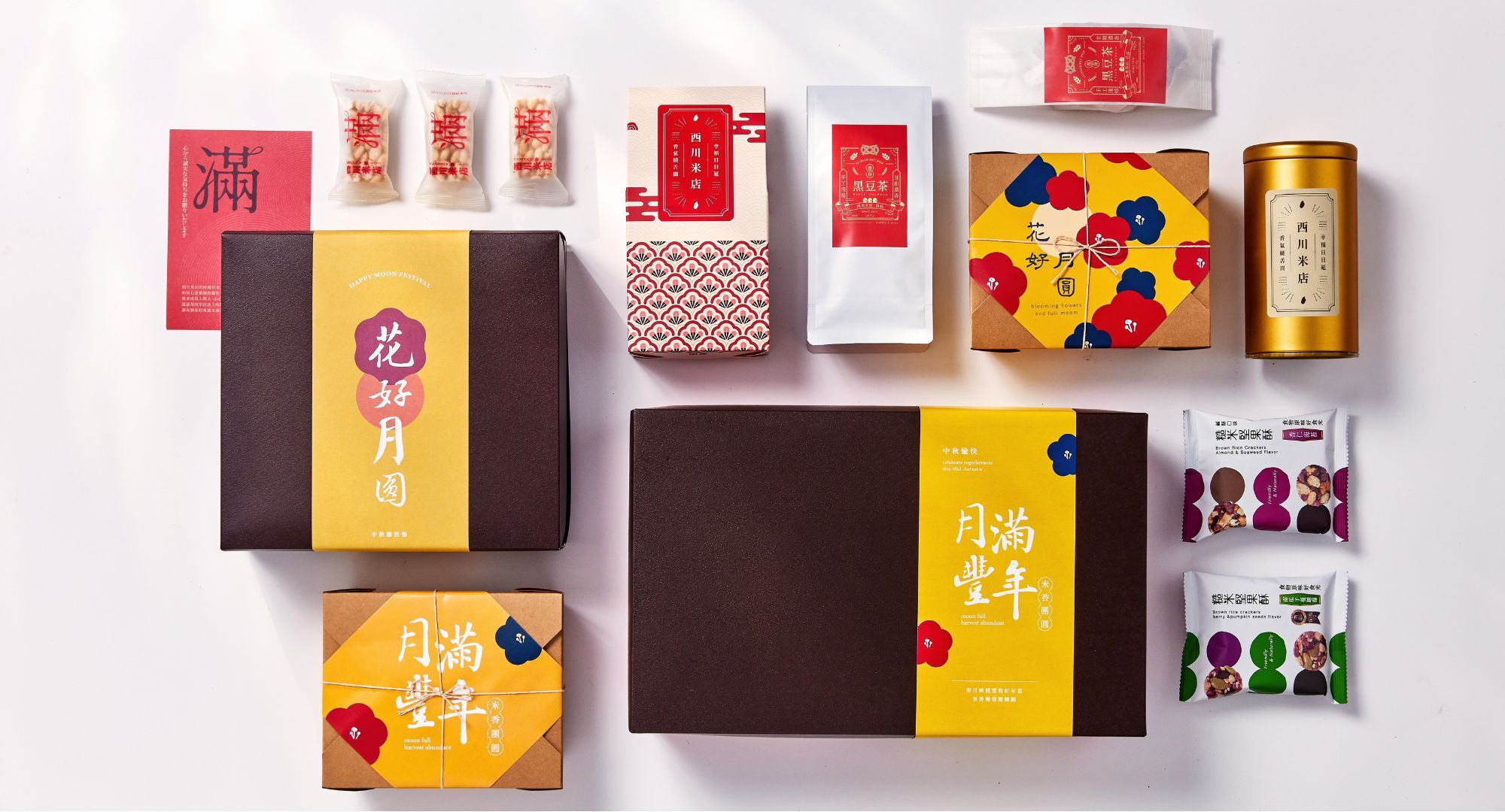 花好月圓中秋禮盒組,在白色背景上,中秋禮盒內由右到左依序放著四包堅果酥、一包穀物飲品與一包米香棒,旁邊搭配紅色手提紙袋與滿字賀卡。