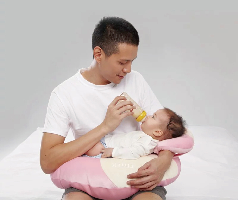 爸爸將寶寶放在月亮枕上餵奶