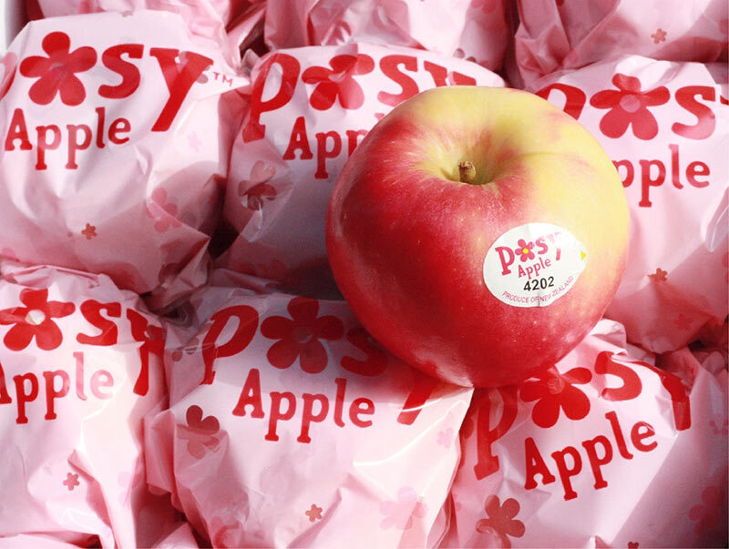 入厝禮推薦，一顆新鮮紅潤的蘋果，放置在一堆以粉紅色「Posy Apple」字樣與小花圖案包裝紙包裹的蘋果上。