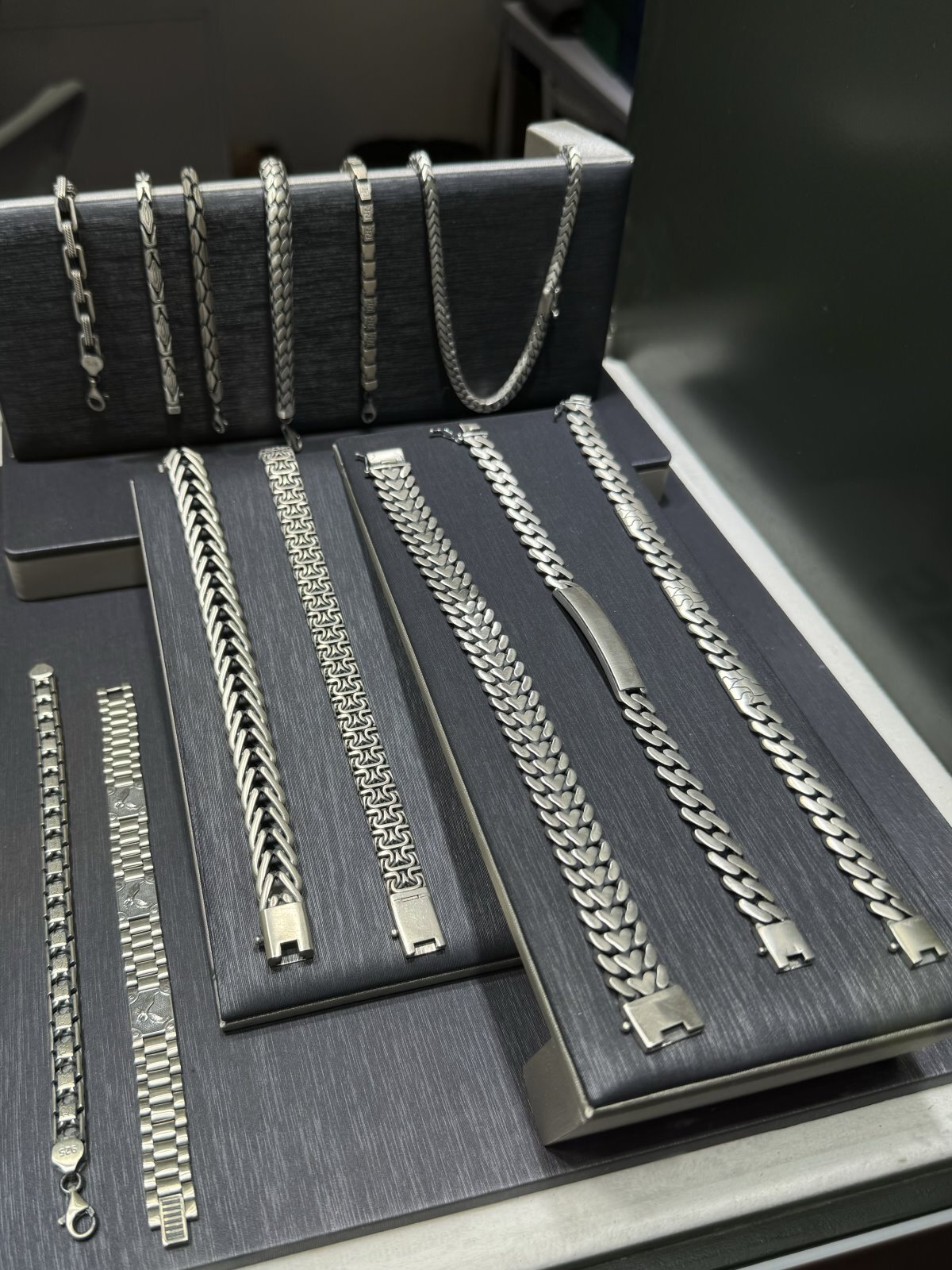 Pulseras y cadenas de plata gruesas para hombre, exhibidas en soporte oscuro