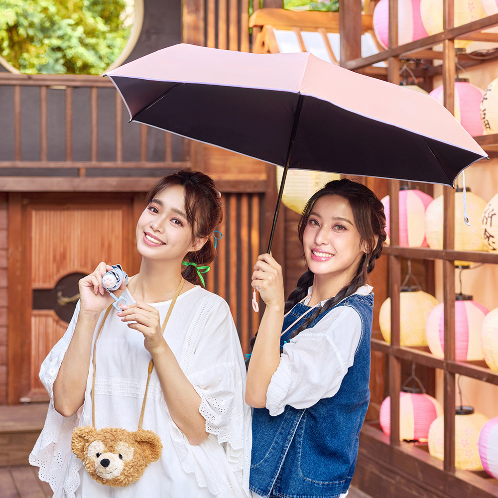兩位女醒開心的展示自動傘，一位手托收合的藍色自動傘，另一位撐開粉色的傘