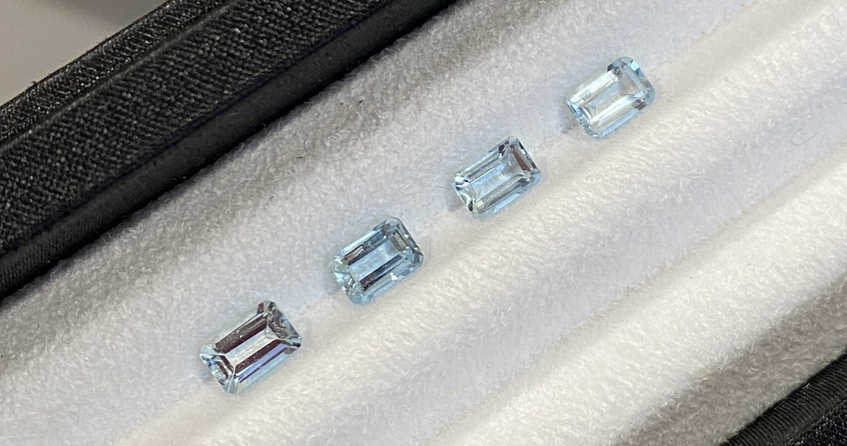 Four emerald-cut aquamarine gemstones with beautiful blue color.
