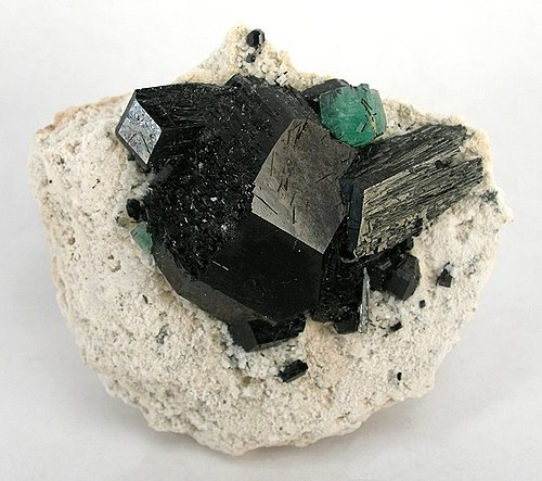 A single stark green fluorite isolated on top of schorl crystals.