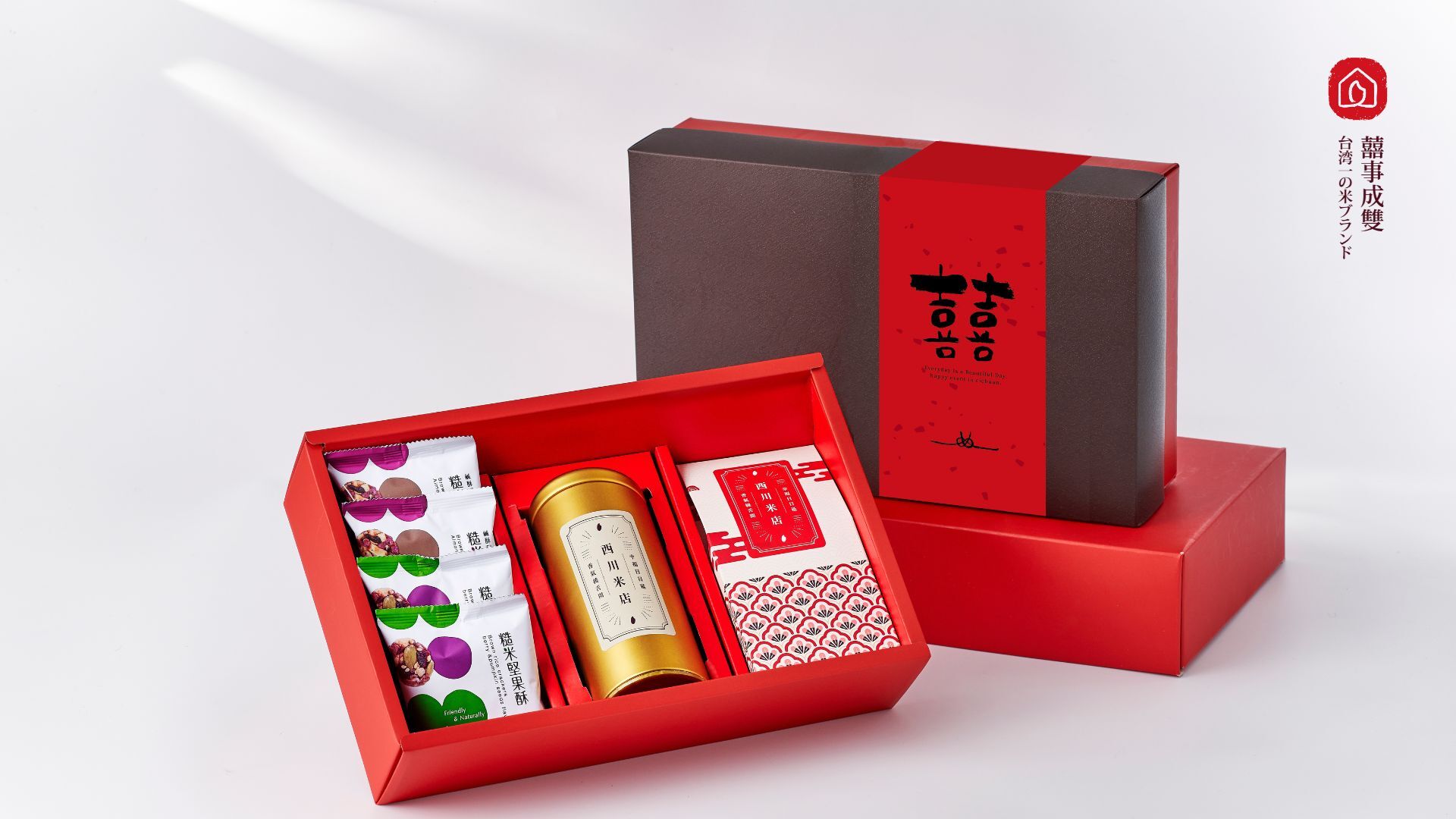 囍事成雙喜餅禮盒組,袖套是雙喜字配上喜氣的大紅色,喜餅禮盒內由右到左依序放著四包堅果酥、一包穀物飲品與一包米香棒,旁邊搭配紅色手提紙袋與滿字賀卡,白色光影背景。