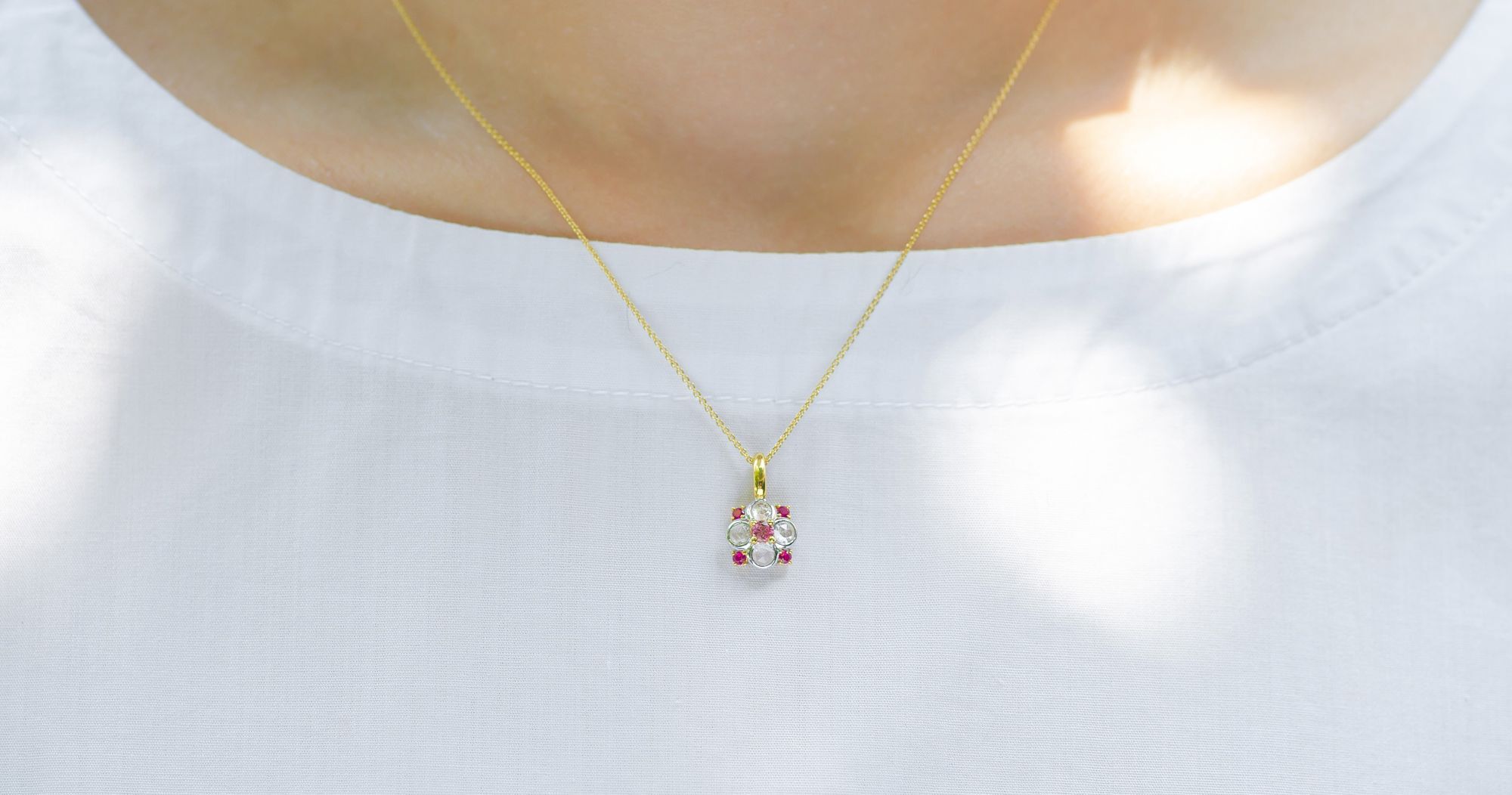 Art Nouveau-style necklace featuring rubellite tourmalines and diamonds set in a delicate floral pendant on a gold chain.