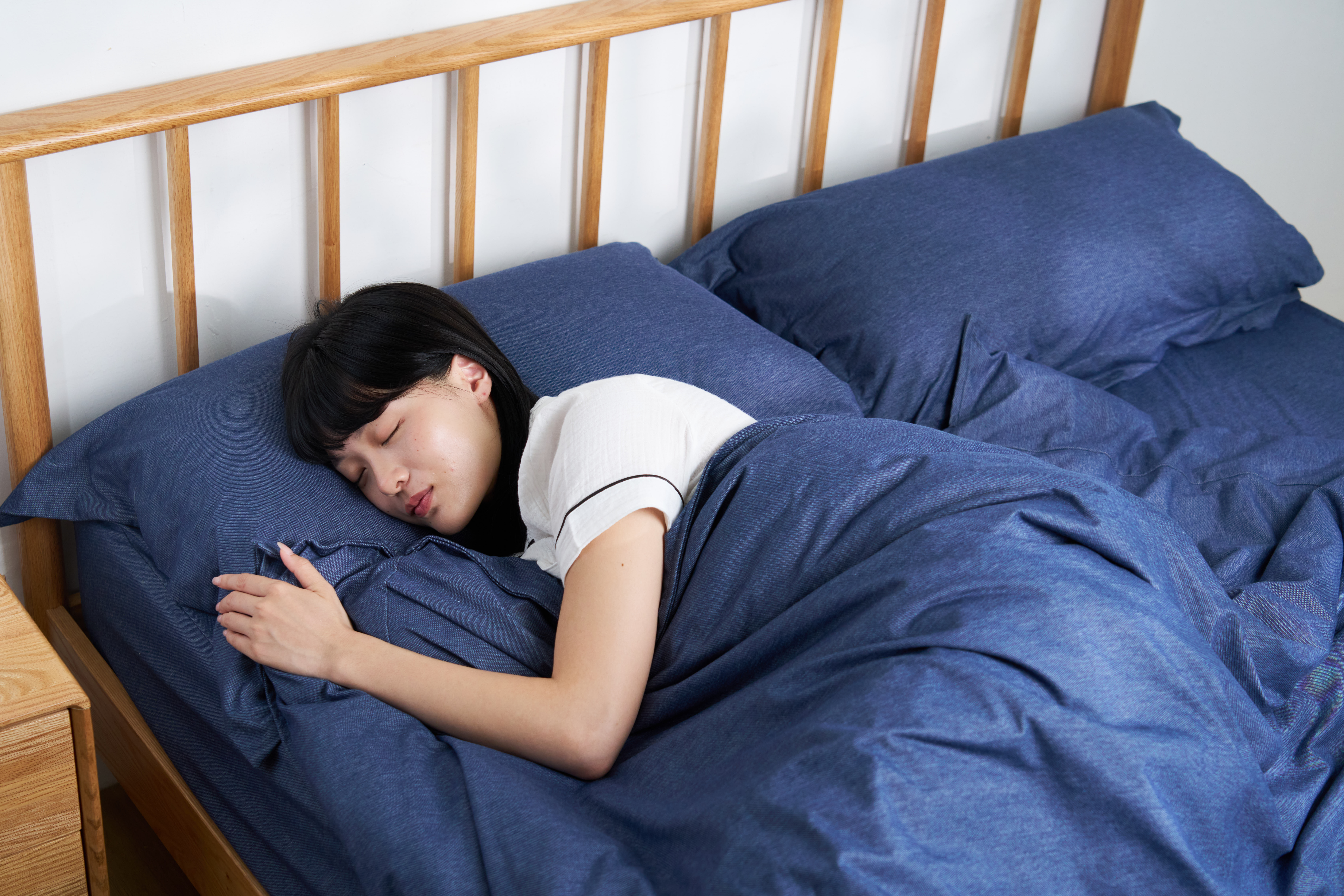 一位女孩躺臥在包覆牛仔布質料的寢具組床上