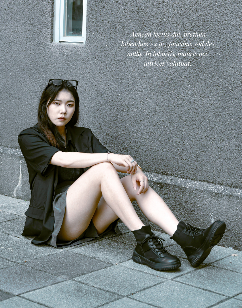 Sanly Joy 克洛伊厚底真皮短靴經典黑形象照。模特以率性姿態倚靠牆邊,展現冷調都會感。鞋款結合真皮與彈性襪筒設計,穿著柔軟不緊繃。5cm厚底提升比例修飾腿型,兼具時尚與舒適。整體搭配簡約俐落,展現女性自信與氣場。