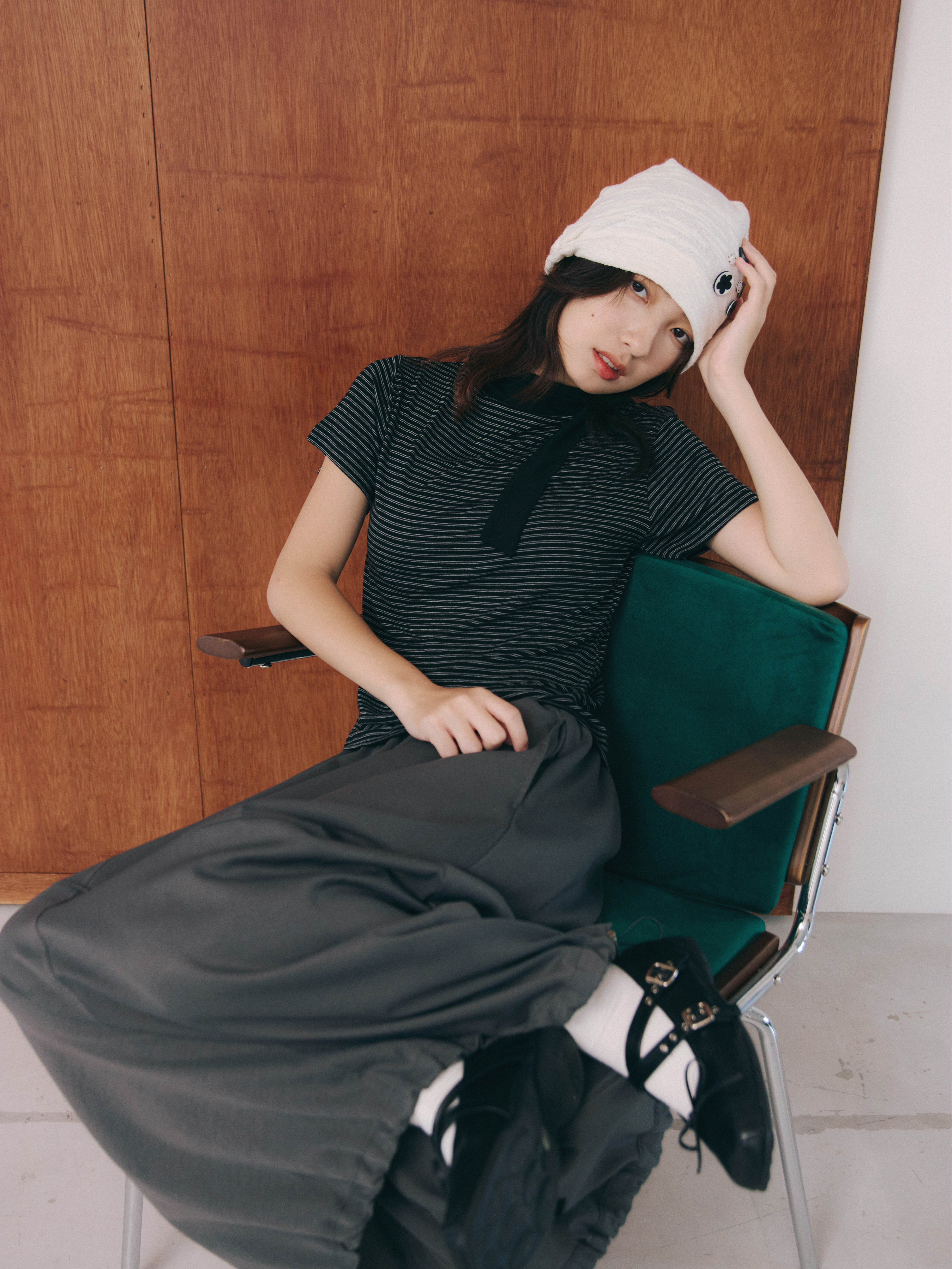 女孩帶著堆堆帽，上身搭配條紋圍巾上衣，下身穿著類似氣球裙版型得縫線裙，乾淨時髦。