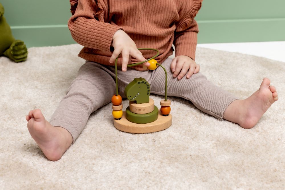 撥珠台以綠色恐龍頭為中心，連接著綠色的金屬軌道，軌道上有黃色和橘色的木珠正在被寶寶的手指撥動。