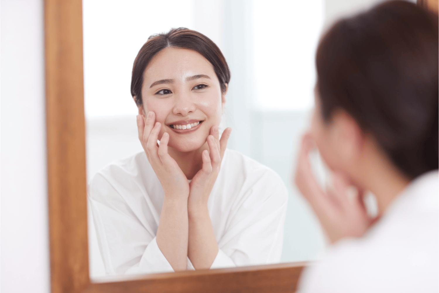 照鏡子微笑的女性，展現光澤健康的肌膚，象徵保養後肌膚穩定與自信