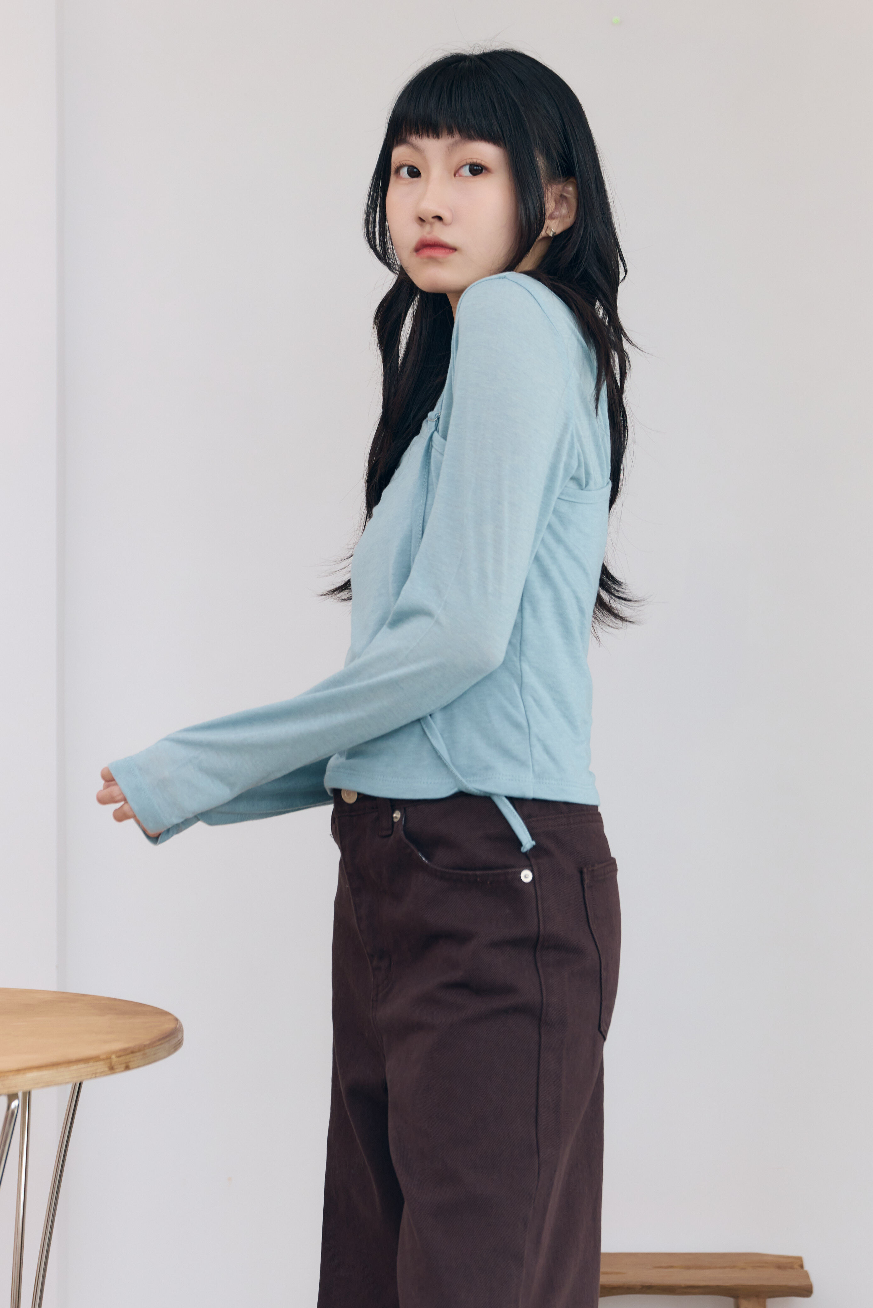 女孩穿著綁脖樣式的上衣，顏色是水藍色，層次造型的上身款式非常獨特。