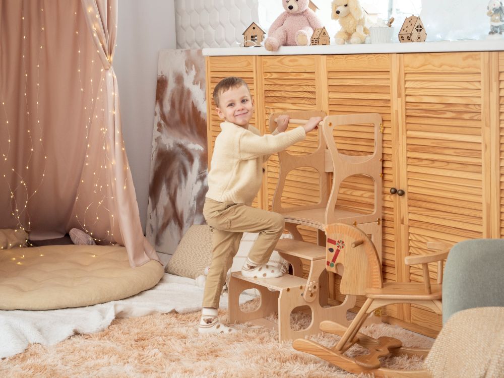烏克蘭 Wood&Hearts 2ways 蒙式學習塔桌椅組經典款，一名幼兒正在階梯式學習塔上站立探索。