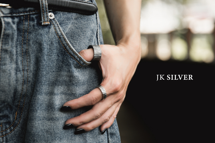 牛仔褲口袋邊的街拍近景,拇指與中指配戴鍛敲紋理足銀戒(寬版+窄版),右側 JK SILVER 字樣