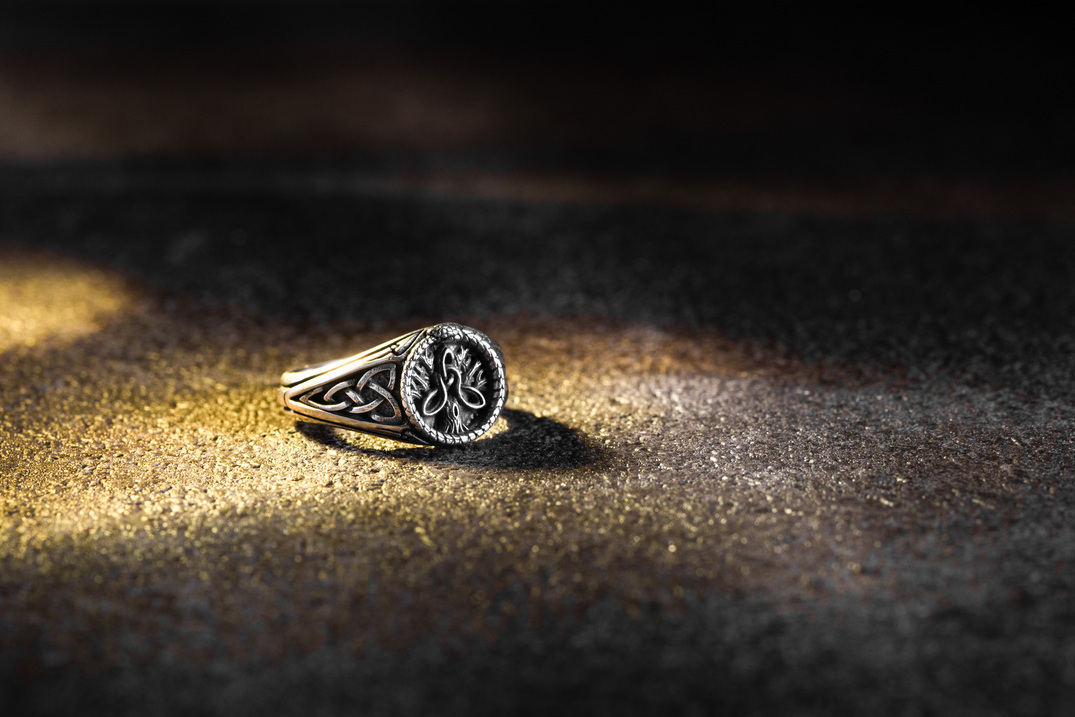 永恆之結純銀戒指特寫,凱爾特三位一體結(Triquetra)圖騰與世界之蛇(Ouroboros)環繞戒臂,在光影中呈現復古銀飾質感