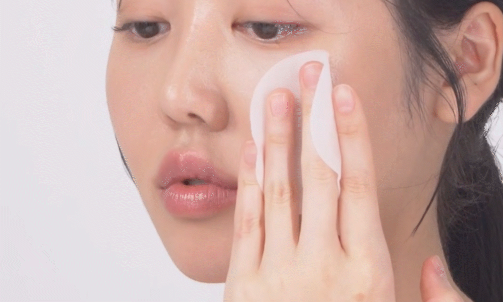 用棉片向外擦拭臉部肌膚的年輕女性