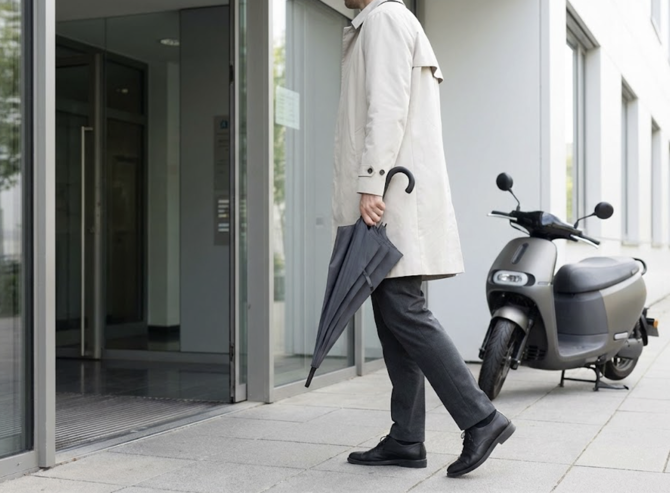 機車停在建物前方，騎士撐著折疊傘優雅走向入口的畫面