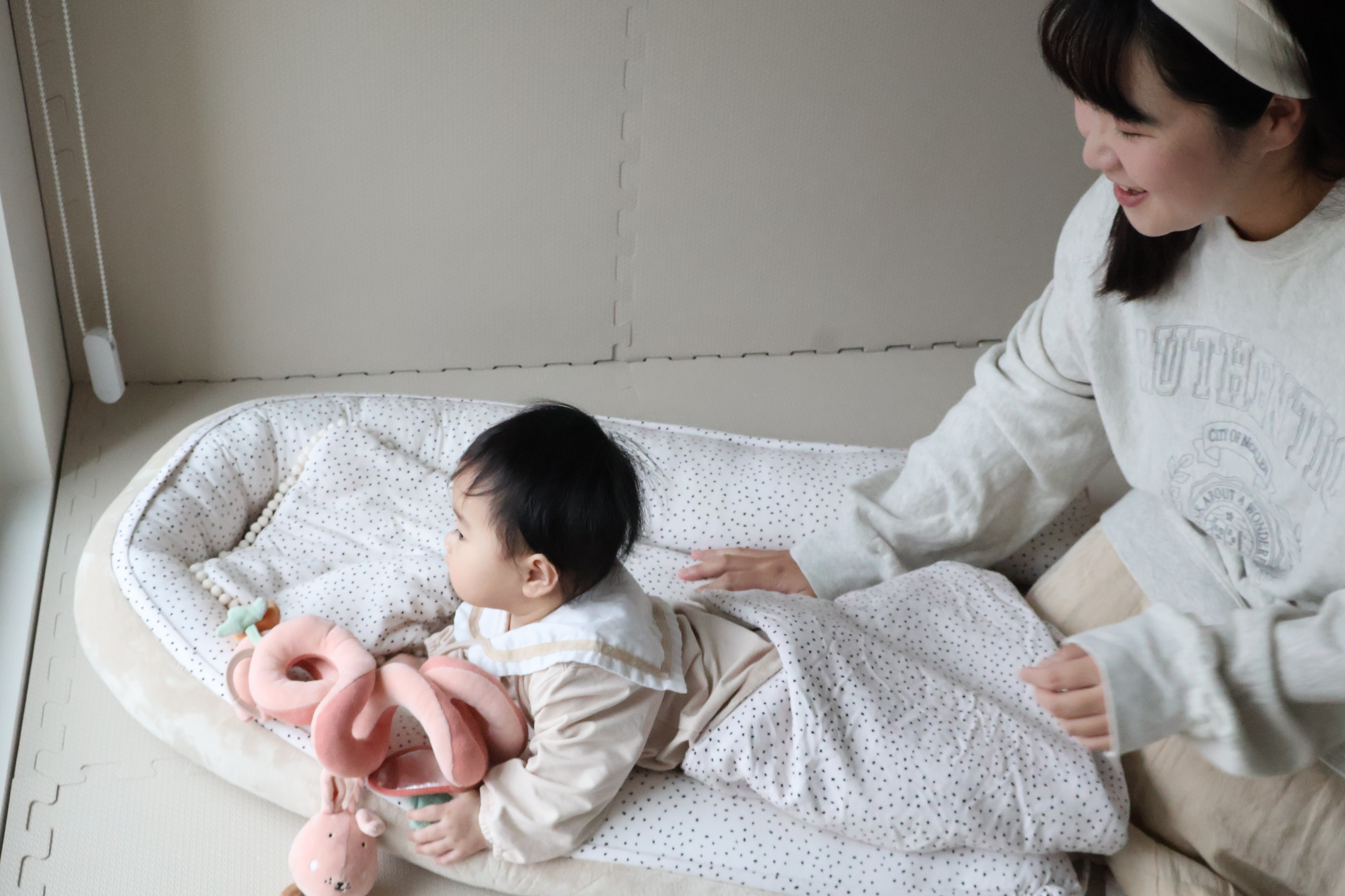 媽媽陪伴寶寶在米蘭暖陽睡窩中探索，寶寶正看向窗外的風景。