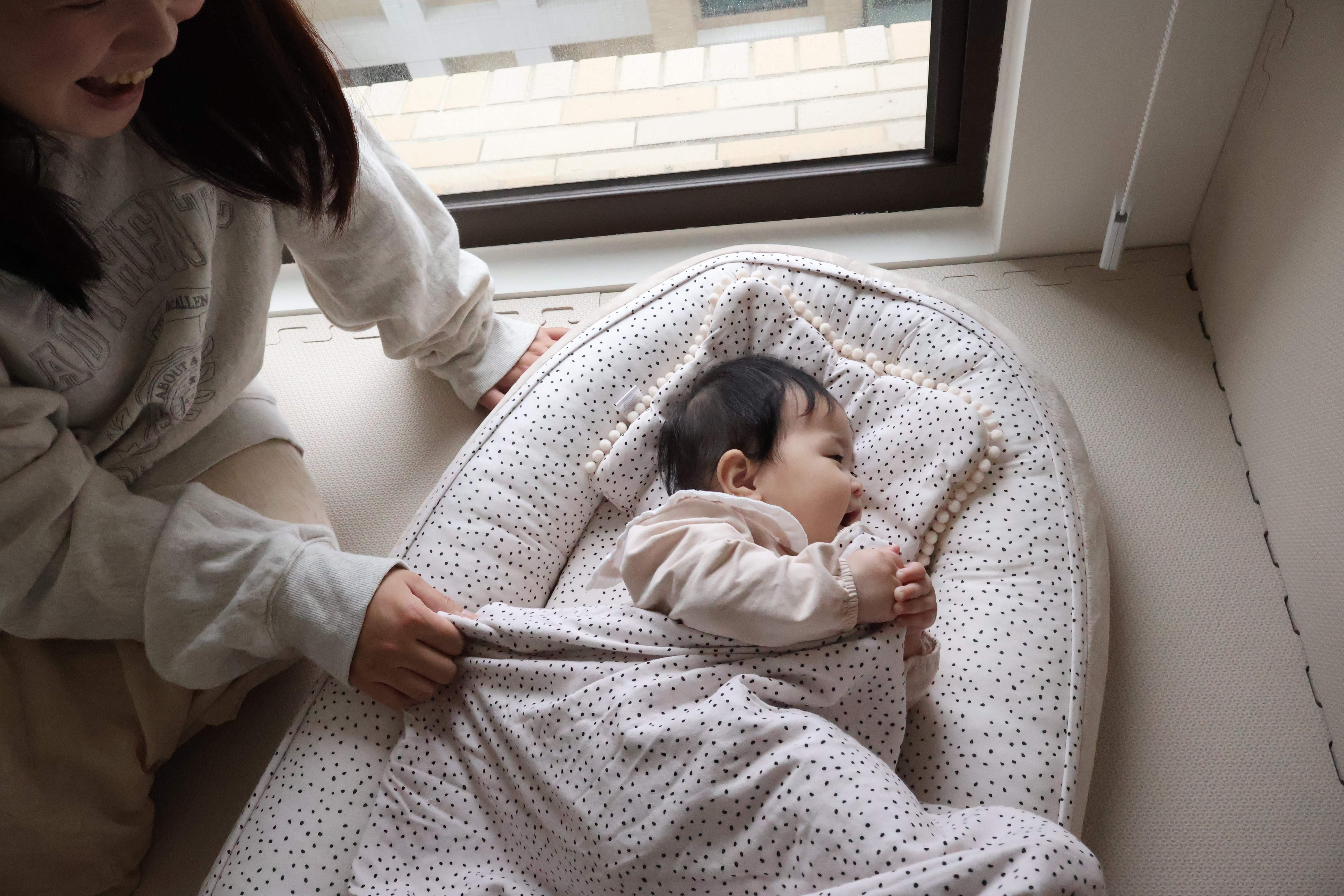 寶寶躺在睡窩中，媽媽幫寶寶蓋好身上的竹纖雪柔毯。