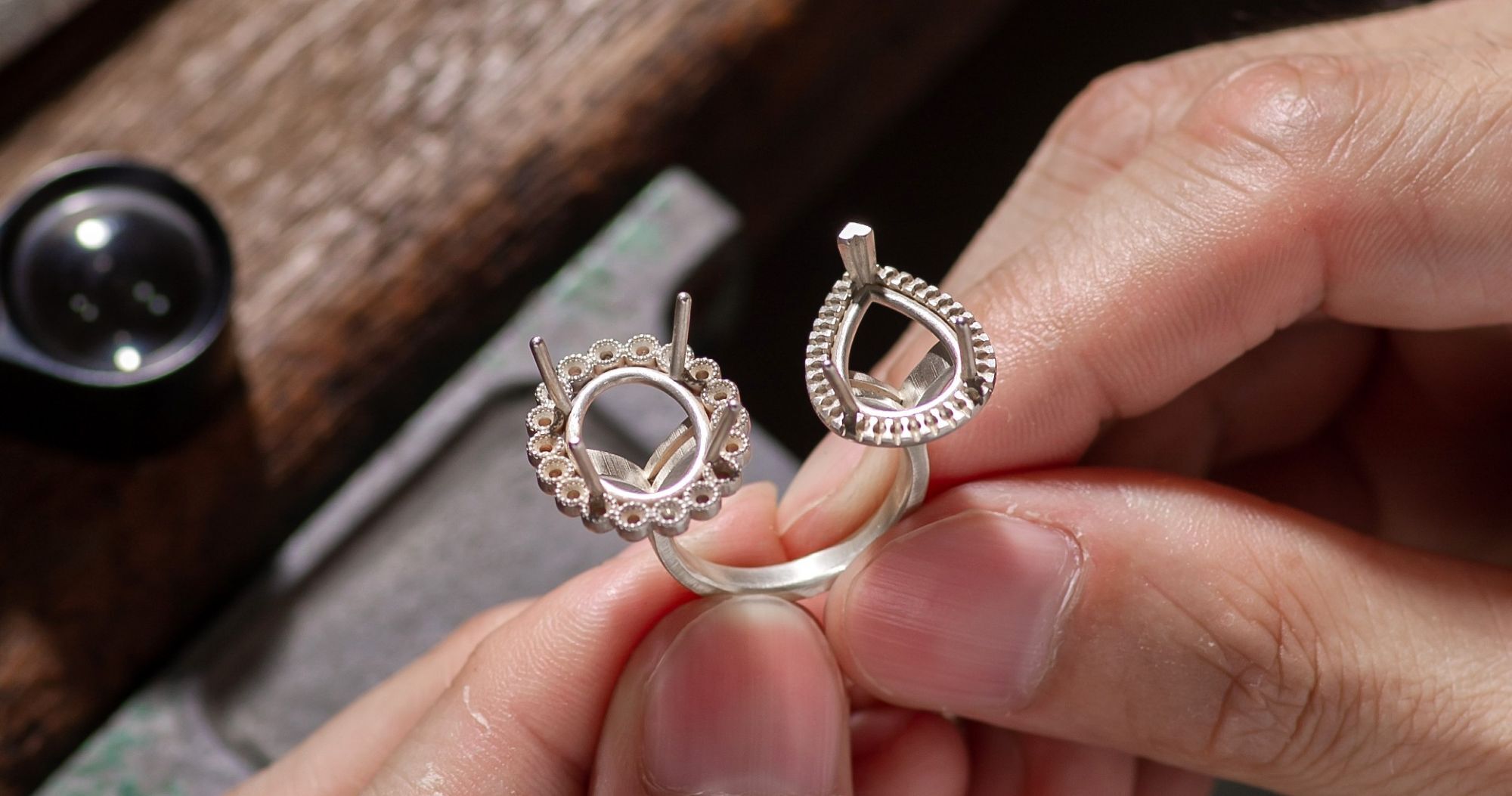 Hands holding a dual-style gold ring mounting with round and pear-shaped settings.