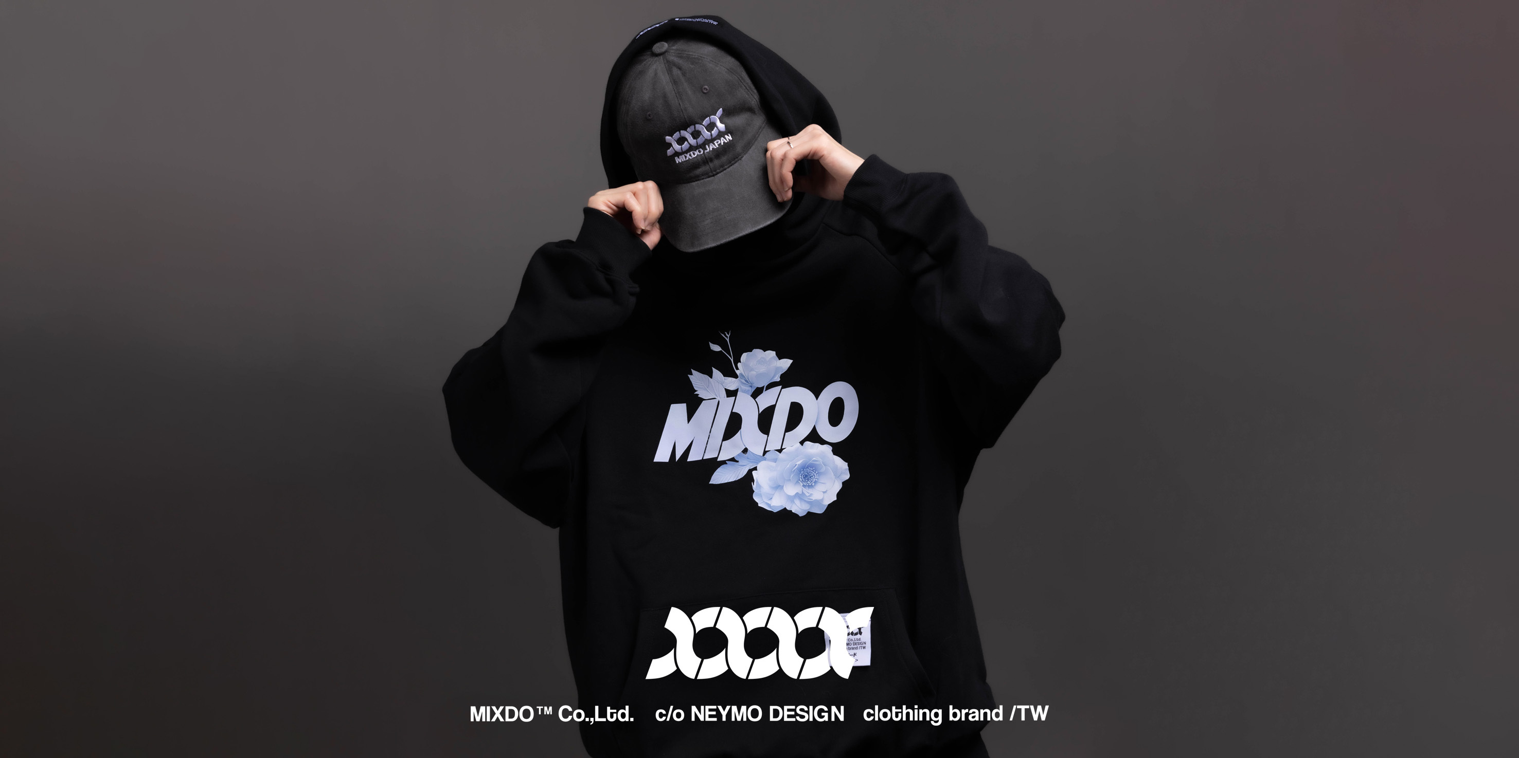 「Gypsum flowers Hoodie/ 石膏花連帽T」設計理念 靜止，也是一種姿態。 這件帽T以 MIXDO 正體 LOGO 為核心，結合石膏雕塑花卉的元素，讓冷調的結構與柔性的生命力產生對話。