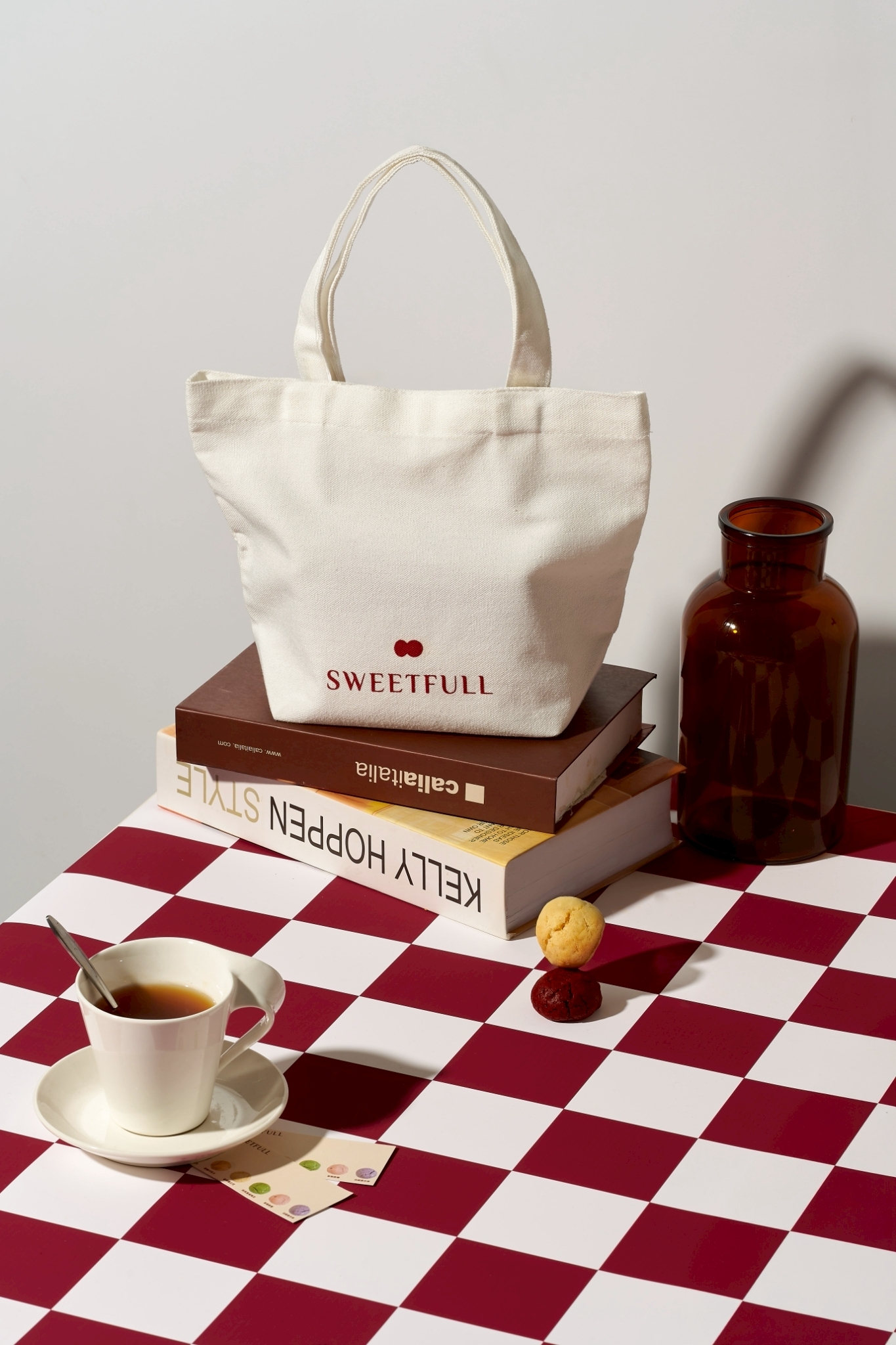 Sweetfull 品牌帆布提袋形象照，置於書本上並搭配迷你軟餅乾與茶杯，呈現溫暖居家風格。