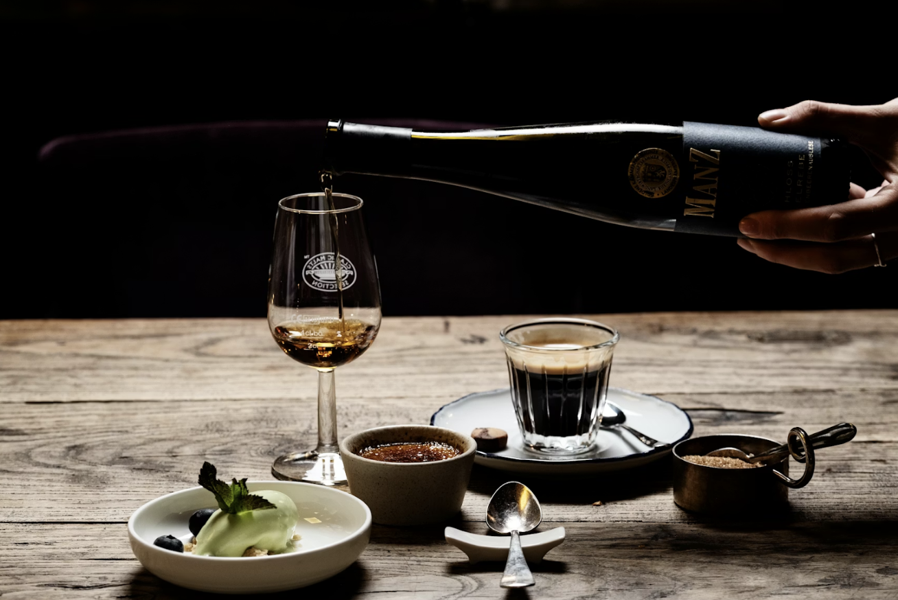 昏暗背景下將酒倒入高腳杯的精緻甜點餐桌場景,營造出成熟而講究的用餐氛圍