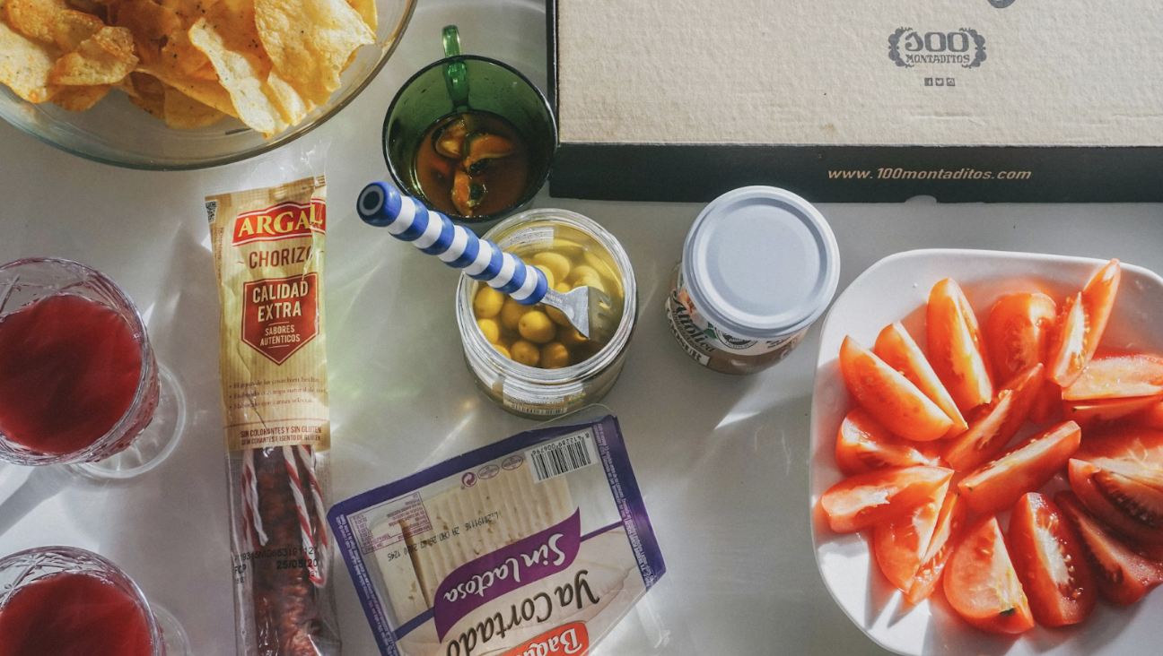 桌面上擺放著零食、香腸、起司、橄欖與飲品,呈現輕鬆分享的小食聚會場景