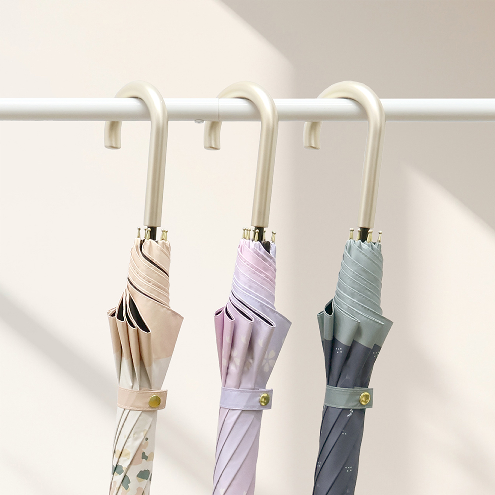 將21吋防曬中長傘日系花影的橘沐、蔚羽及紫櫻掛在白色的長桿上並放置在一間陽光柔和的臥室裡