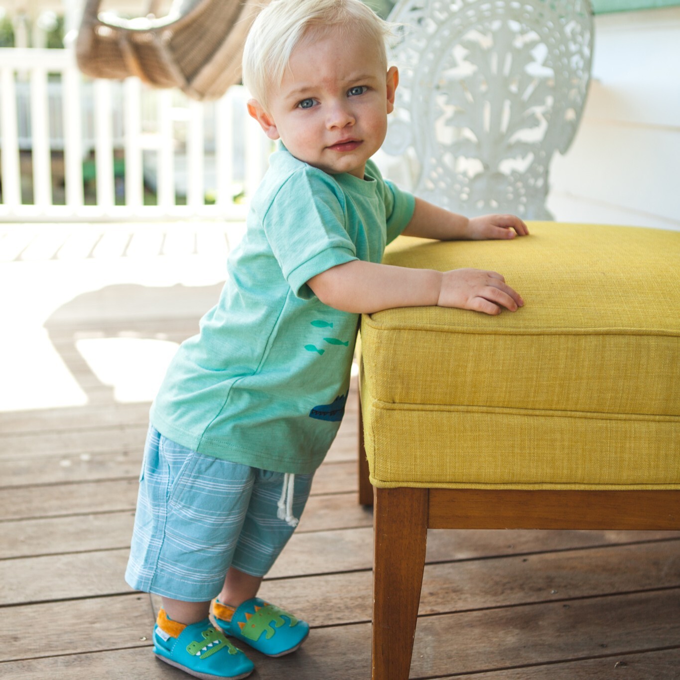 寶寶穿著 Inch Blue經典寶寶鞋在木質地板上爬行與站立，提供裸足般的舒適感與防滑力。