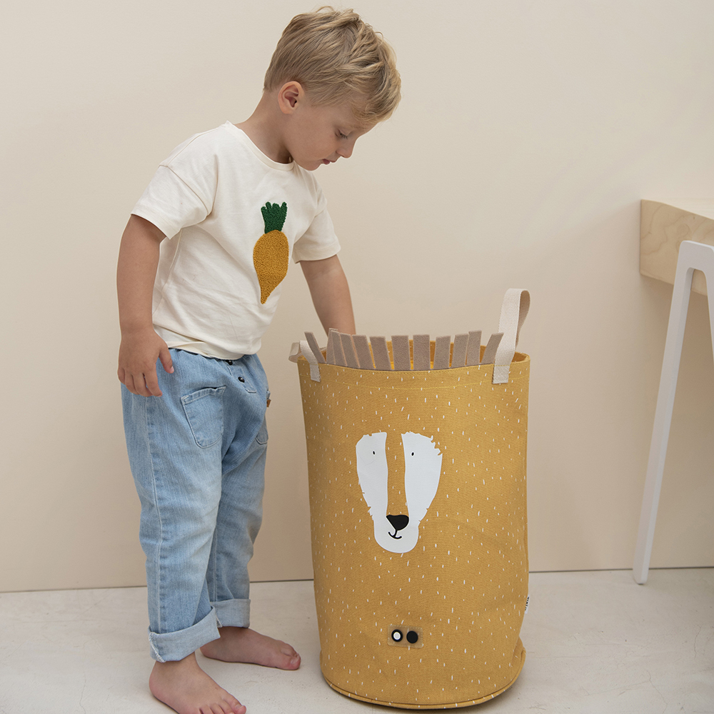 幼兒正將玩具收入黃色獅子造型的比利時 Trixie 多功能收納籃，落地式設計適合訓練收納習慣。