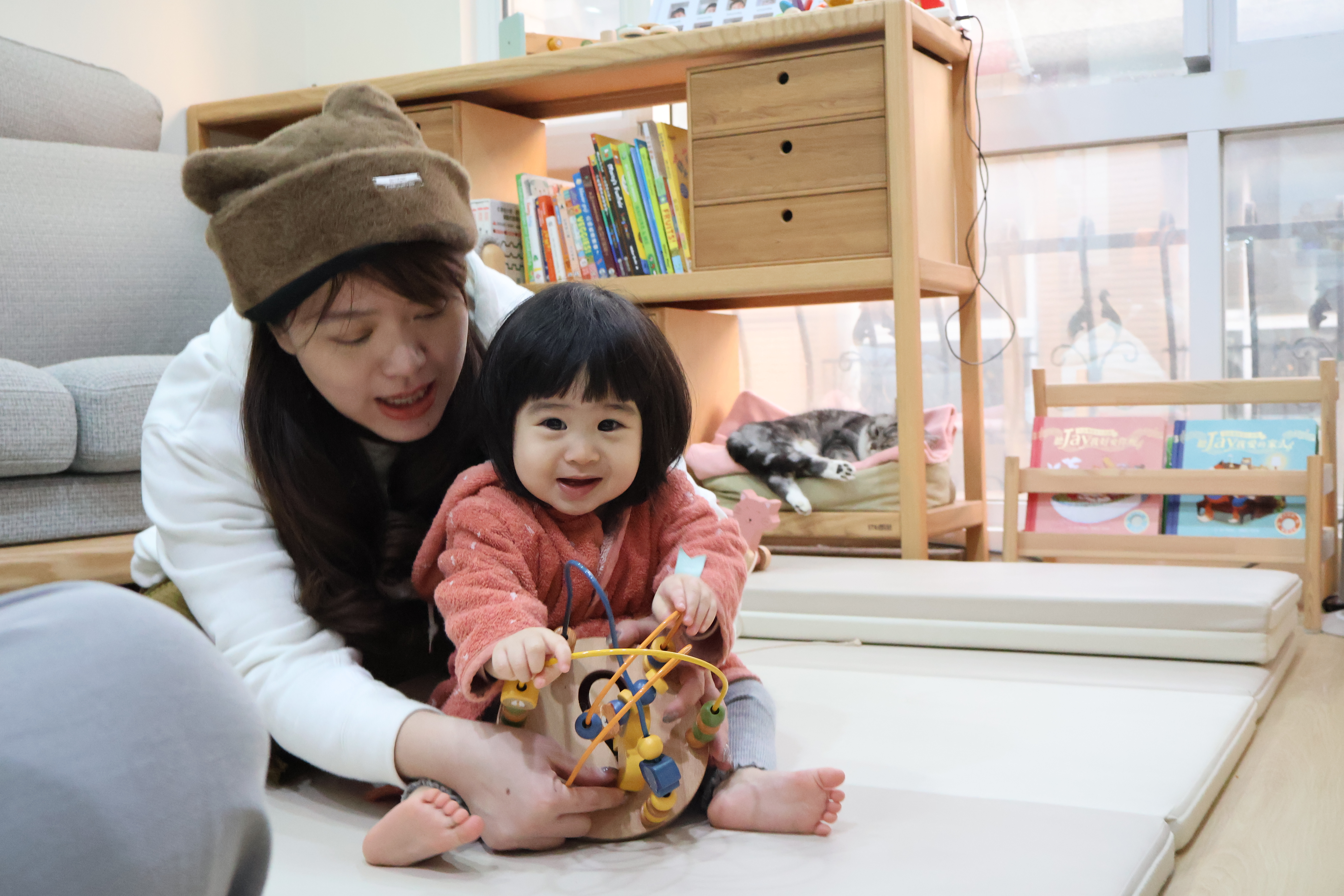軒軒媽媽與小梅子在客廳遊戲空間共玩寶寶玩具的溫馨互動。