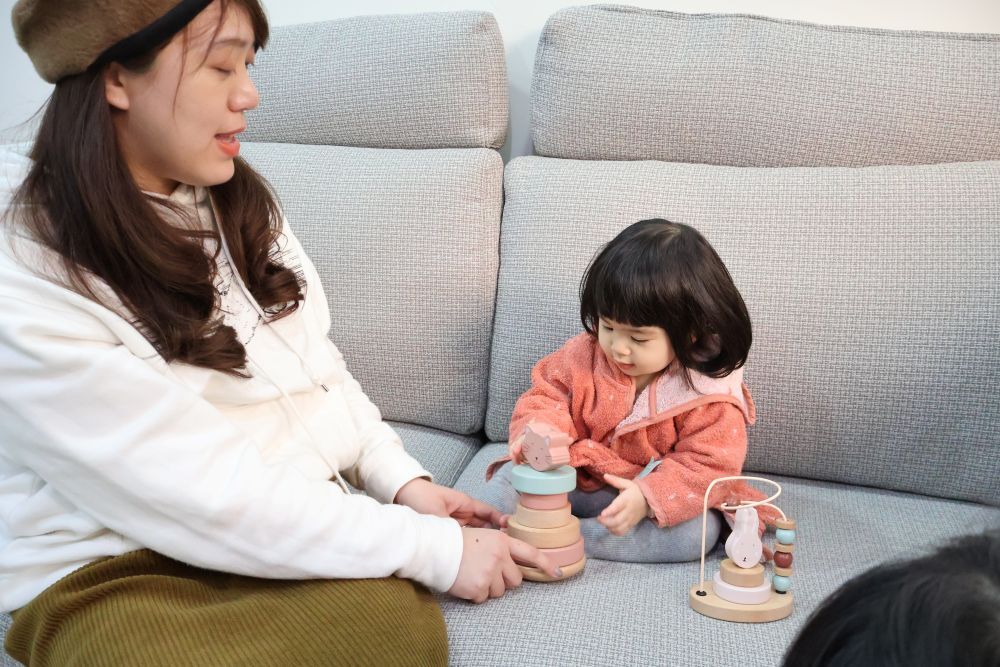 軒軒媽媽溫柔陪伴小梅子玩木製疊疊樂玩具，展現親子共學的居家日常。