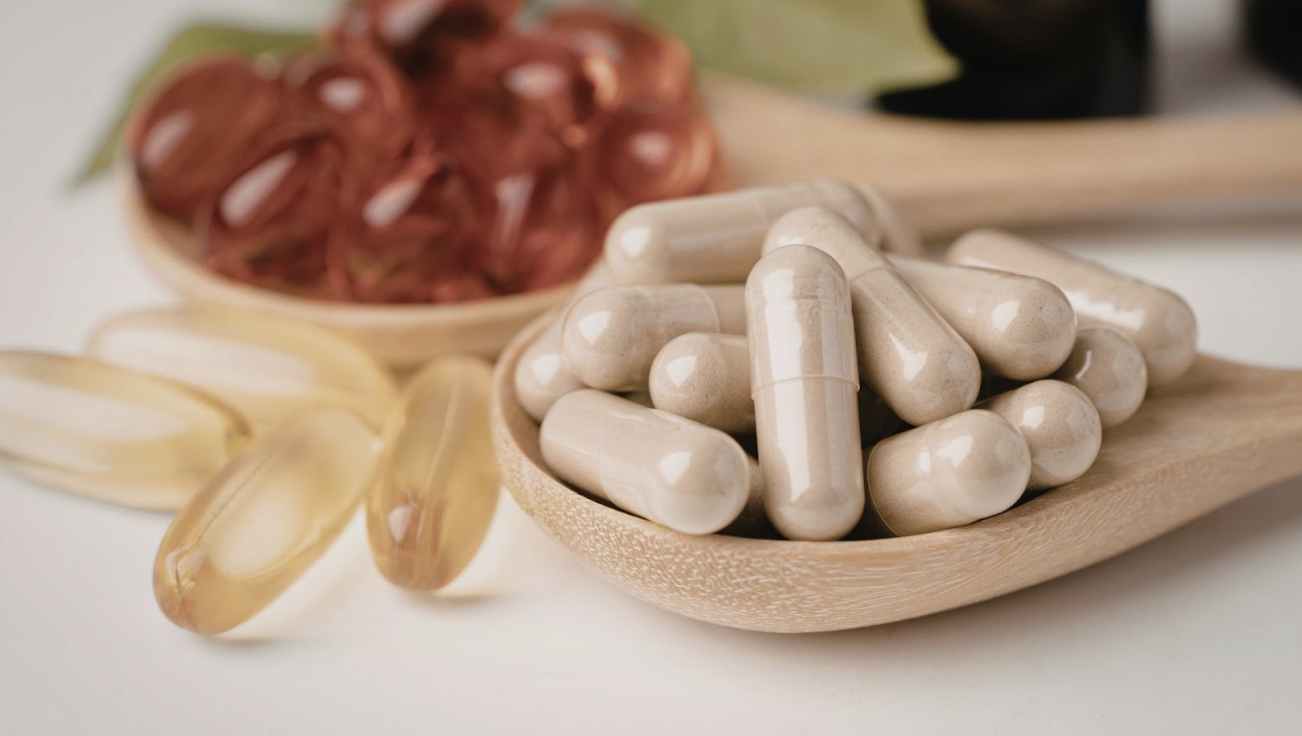 木杓盛裝著多粒米色保健膠囊與魚油軟膠囊特寫，展現高品質的膳食補充劑質感。