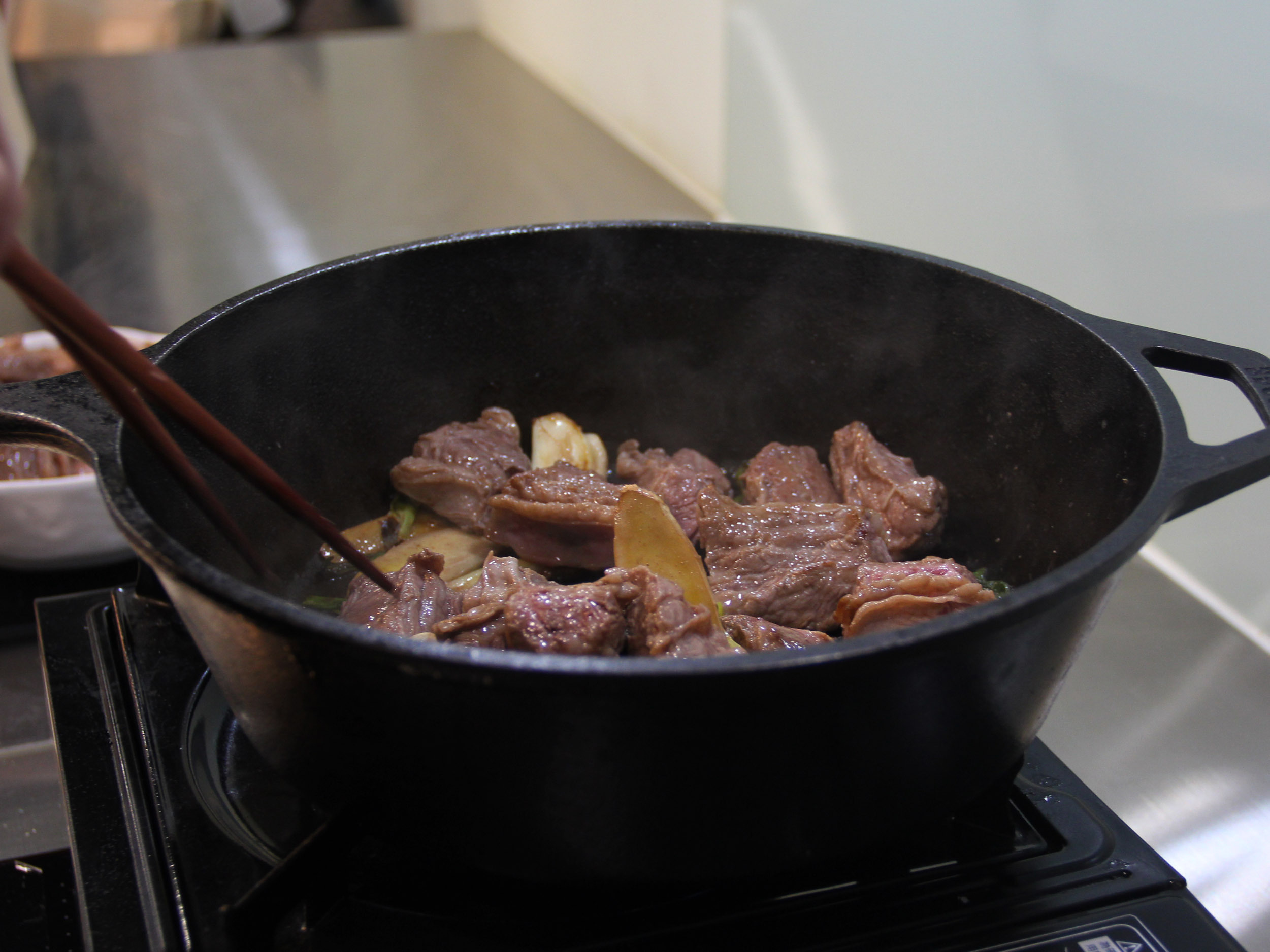 4.利用煎出的油脂炒洋蔥至透明,放入醬油、冰糖、米酒及其他香料、豆瓣醬炒香,倒回牛肉塊