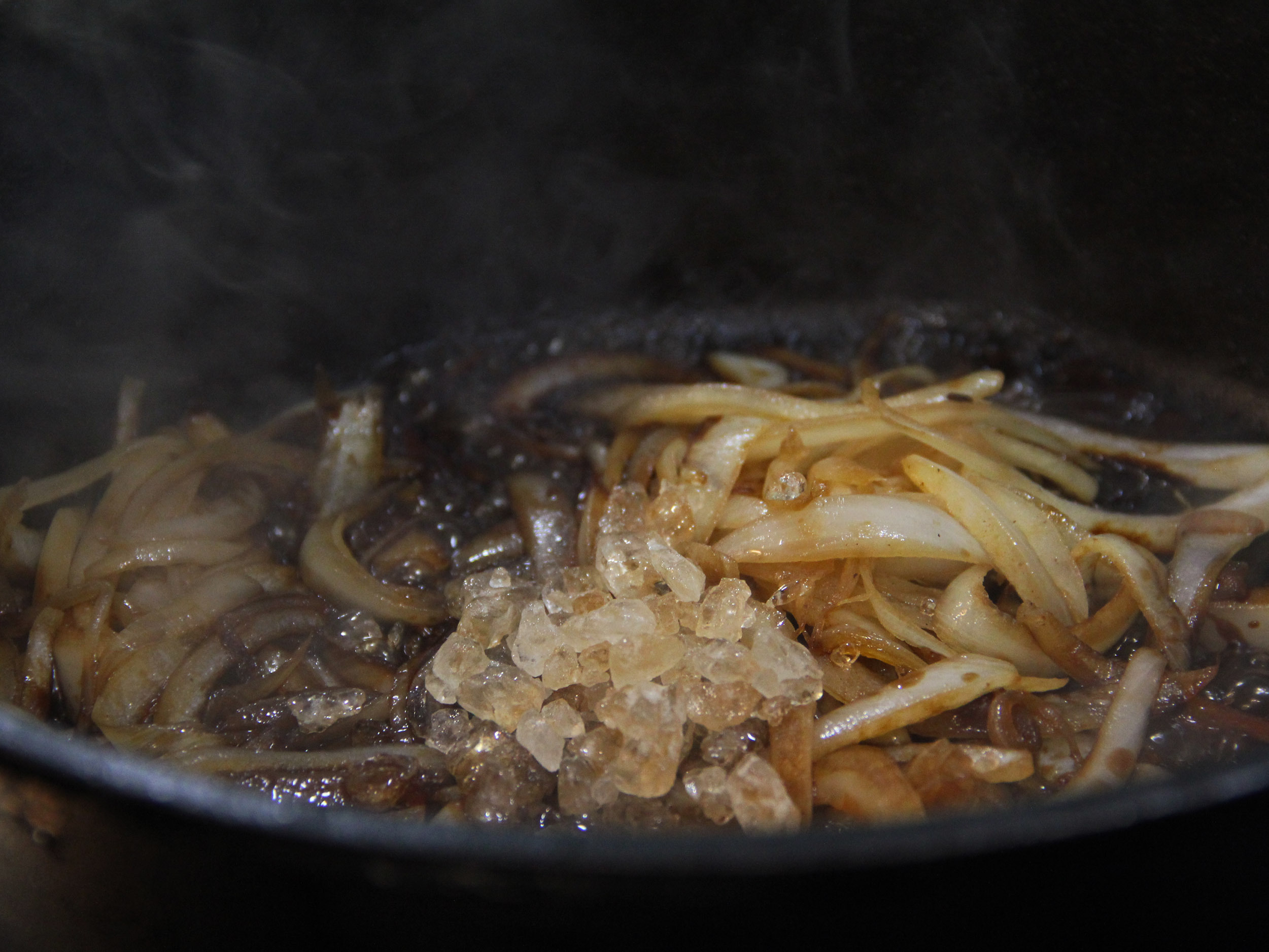 4.利用煎出的油脂炒洋蔥至透明,放入醬油、冰糖、米酒及其他香料、豆瓣醬炒香,倒回牛肉塊