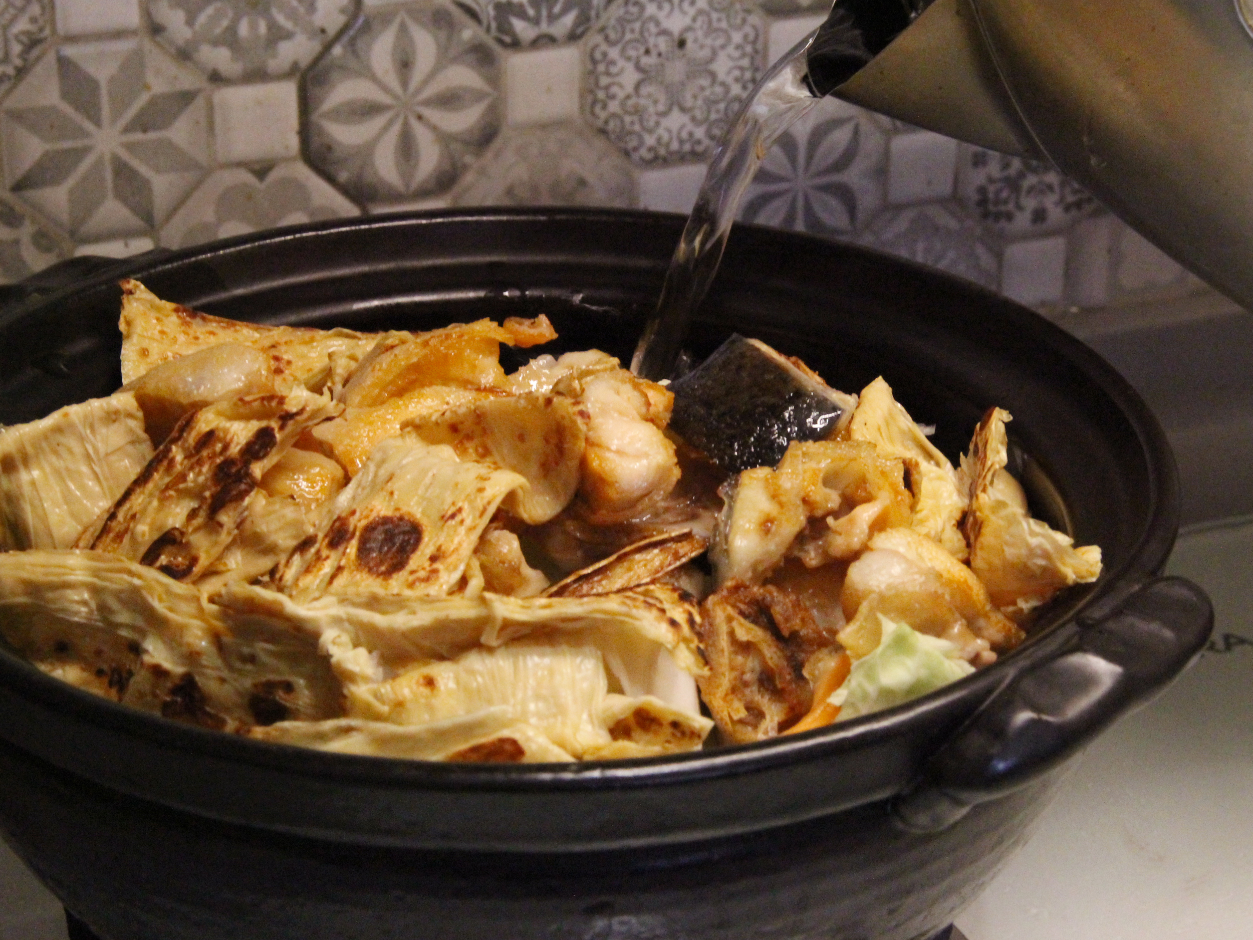 步驟6.再將豆皮、鮭魚頭放入，加進約鍋容量1/2-2/3的水