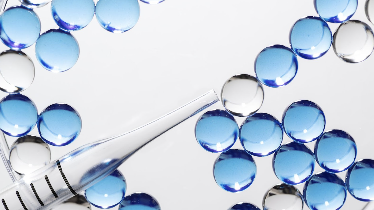 藍色與透明的微小球體排列在一起，滴管尖端對準其中一顆球體，象徵小分子載體技術。