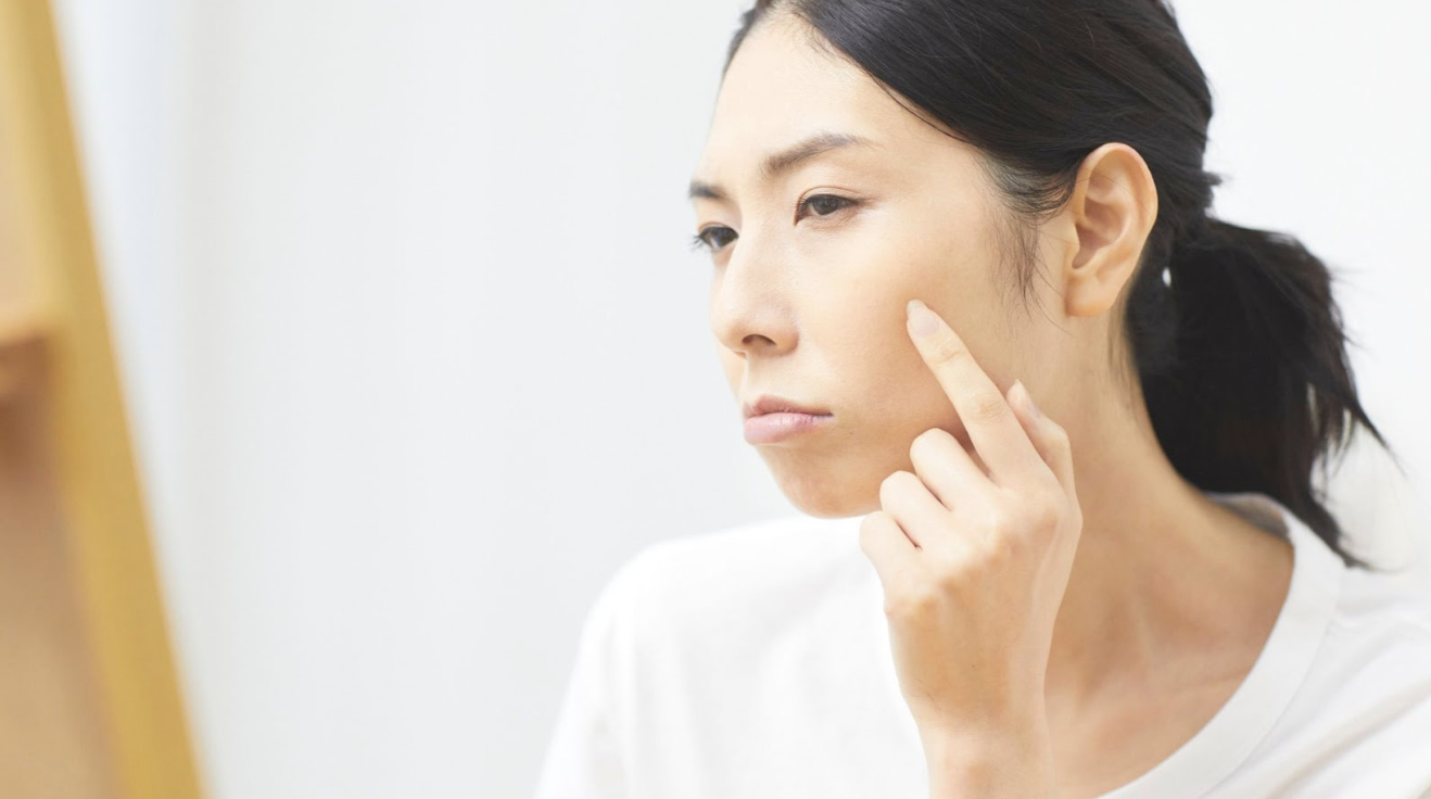 一位女性用左手食指點摸著左臉，做出嘟嘴樣