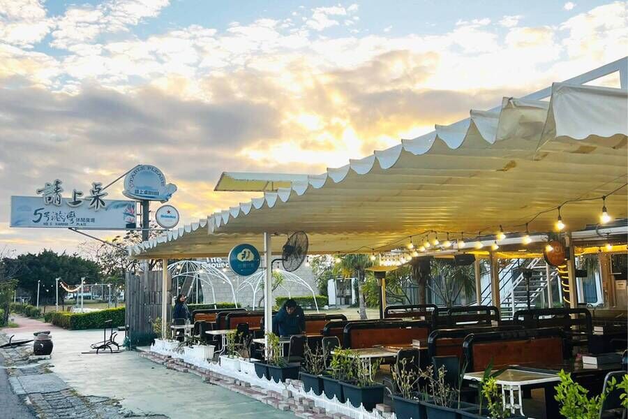 「請上車 5號港灣」景觀餐廳的半露天用餐區，黃昏時分的雲彩與溫馨的燈泡串相映