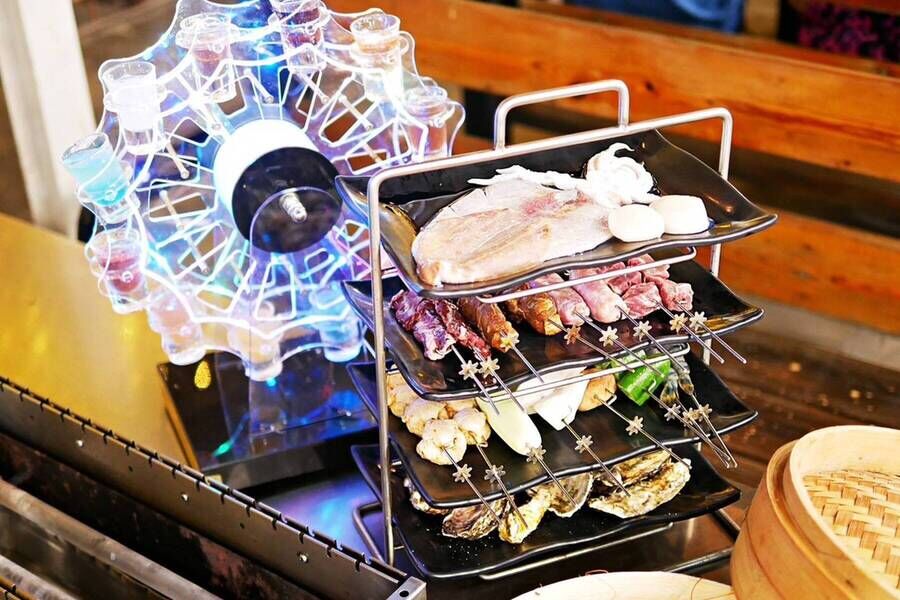 居酒屋創意餐點組合：發光摩天輪調酒與四層架綜合串燒，包含烤魚、肉串、蔬菜及生蠔。