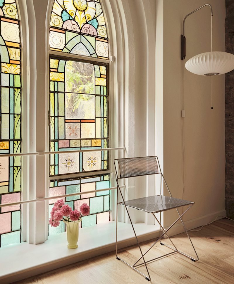 HAY X-Line Chair 於教堂彩繪玻璃窗前。幾何的現代感與 1850 年的石砌拱窗,在同一個光線裡共存。