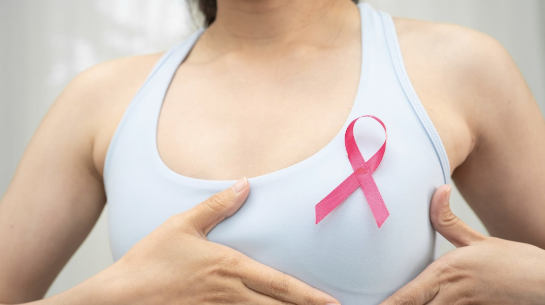 一名女子穿著運動內衣,胸前別著粉紅絲帶,宣導乳癌防治與健康檢查的重要性