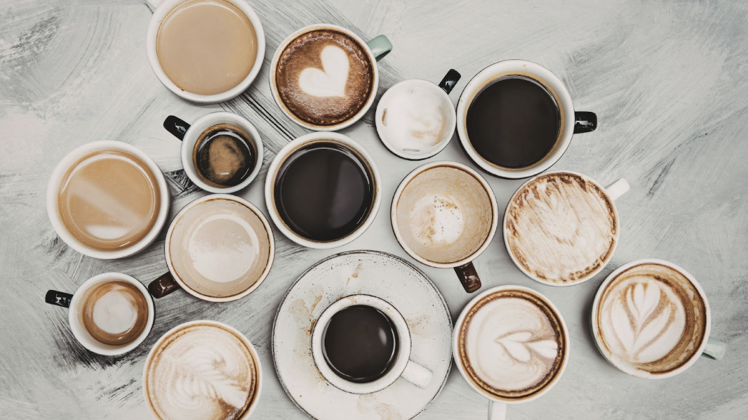 俯瞰視角下多種不同拉花與濃度的咖啡杯群組,包含拿鐵藝術、濃縮咖啡以及喝完後的殘留杯痕